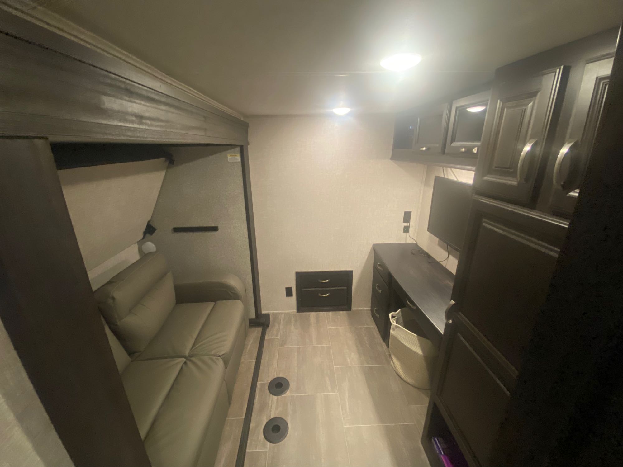 Step inside this versatile rv rental interior, featuring a sofa, functional desk with TV, overhead cabinets, and floor tie-downs.. Jayco North Point 2022