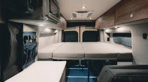RV rental camper van interior: large bed, overhead storage, microwave, and bright lighting for your travels.. Storyteller Overland Beast Mode 2023