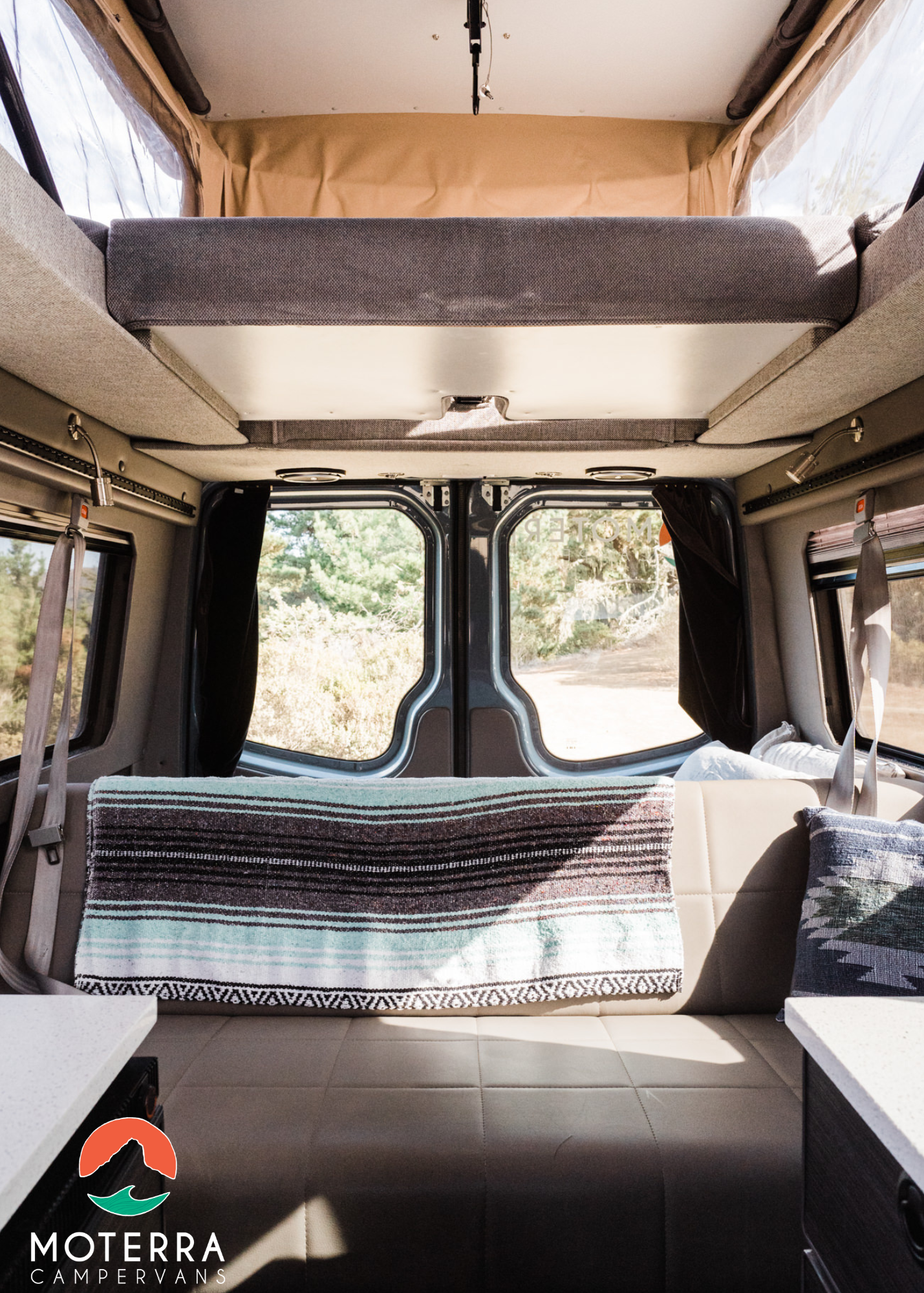 Modern RV rental interior: pop-top bed, comfortable bench seating, and scenic views through the rear windows.. Mercedes-Benz Sprinter 2020