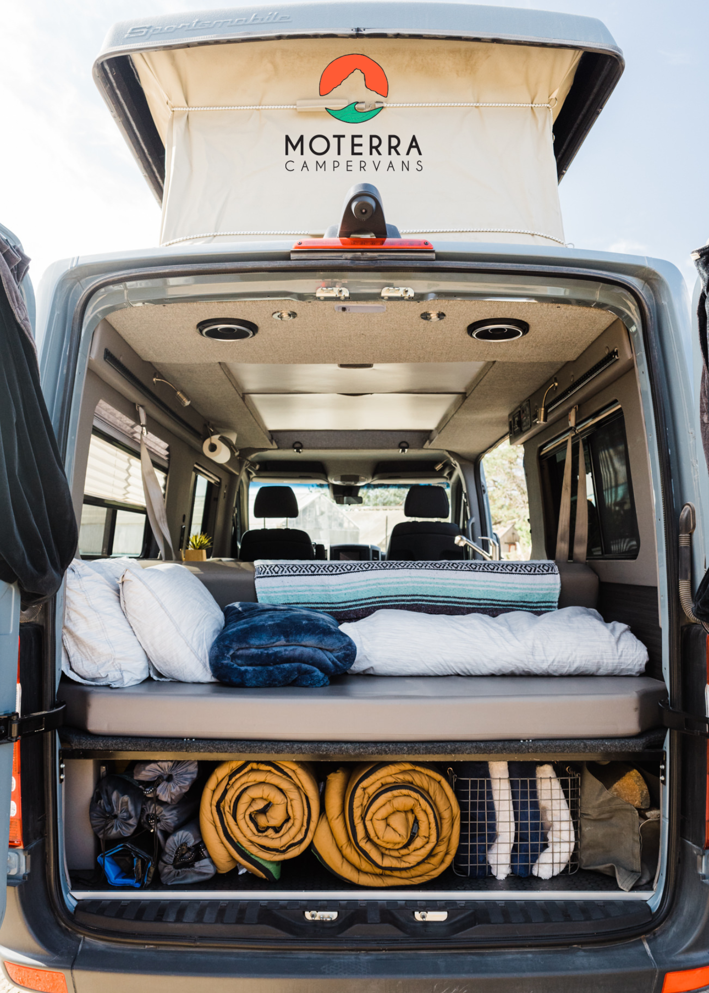 Well-equipped camper van interior for your next RV rental adventure, showing bed & organized storage. Perfect for road trips!. Mercedes-Benz Sprinter 2021