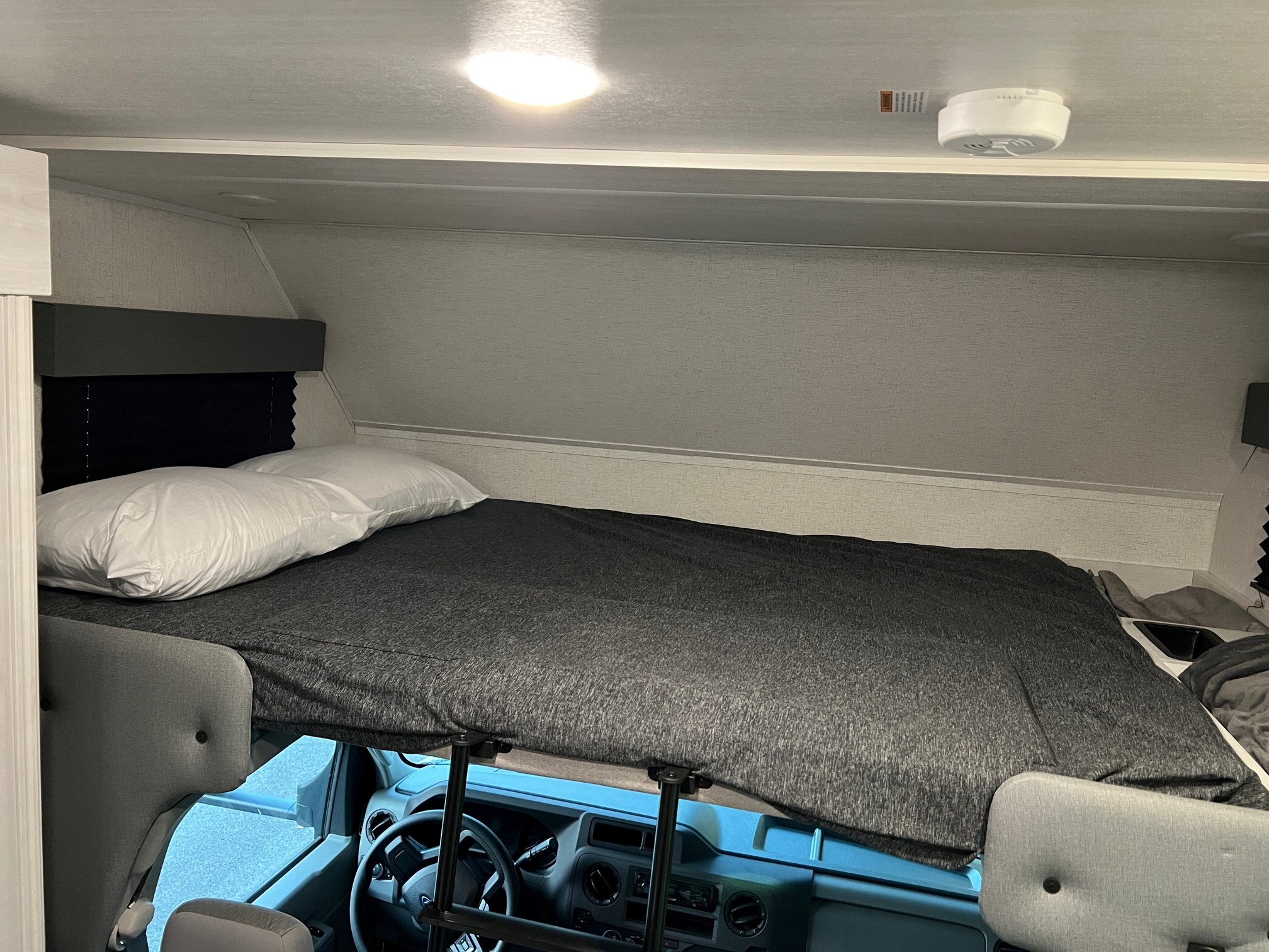 RV rental interior: A neatly made cabover bunk bed with pillows, positioned above the driver's cockpit for extra sleeping.. East to West Entrada 2600DS 2022