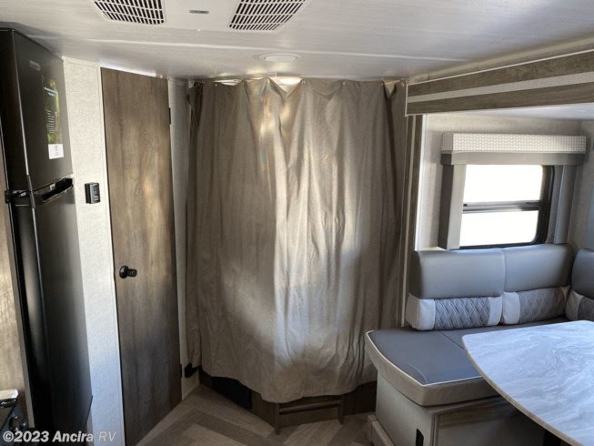 View of an RV rental's dinette area, privacy curtain, and refrigerator, showing a functional and comfortable interior.. Forest River Wildwood X-Lite 2022