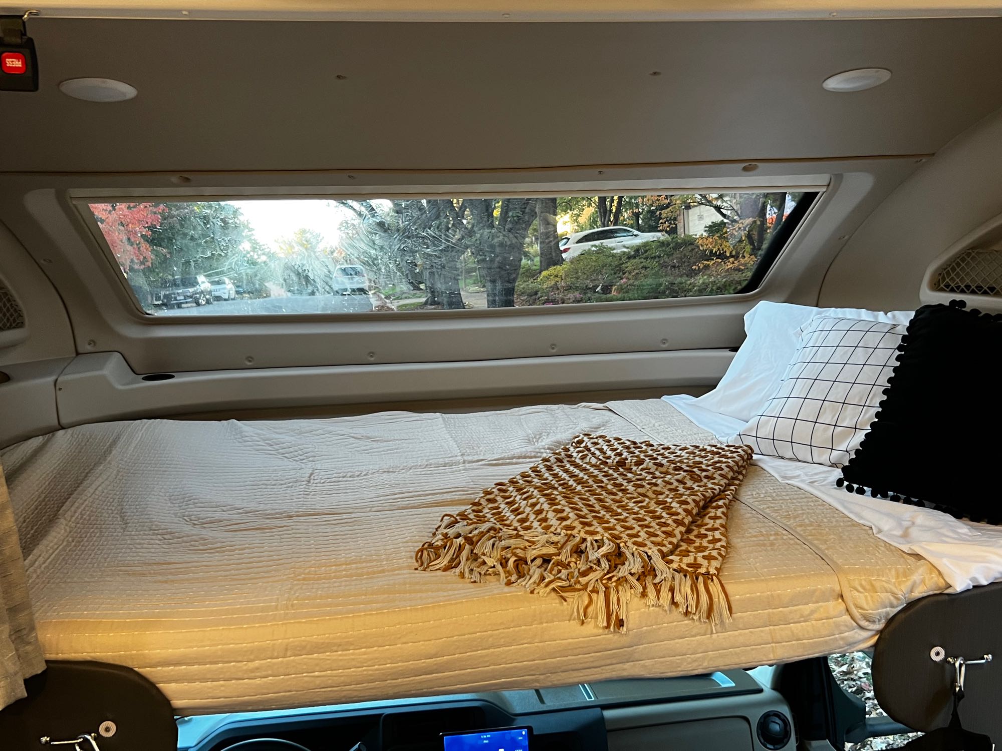 Comfortable RV rental bunk bed with a clear window view of a residential street. Ideal for cozy travels.. Entegra Coach Odyssey 31F 2023