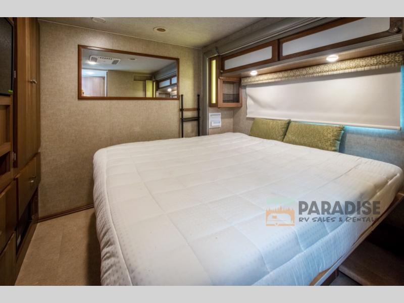 Step into comfort! This spacious RV rental bedroom features a plush bed, ample storage, and ambient lighting.. Winnebago Brave 2016