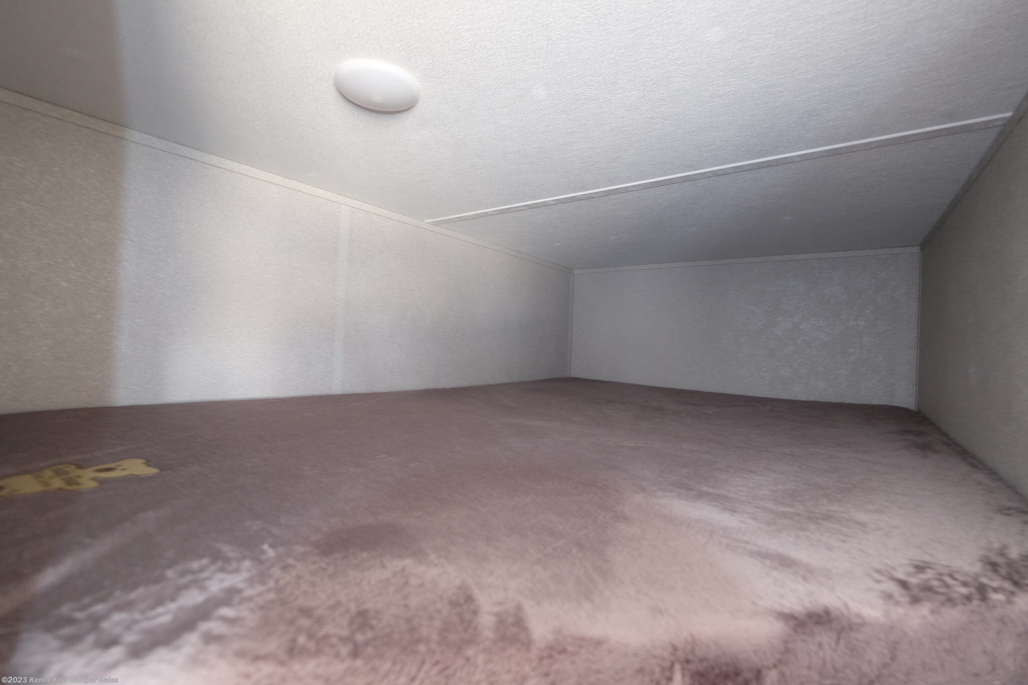 Interior view of an RV rental's cozy bunk area, featuring a soft mattress and ceiling light for comfortable sleep.. Shasta 25RS 2022