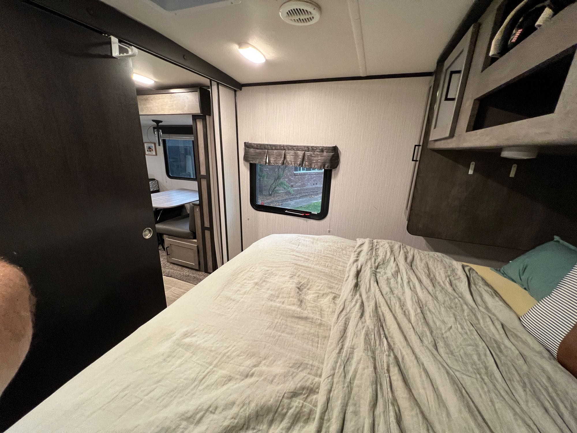 RV rental bedroom interior: cozy bed, window, and a glimpse of the dining area through the open door.. Heartland Wilderness 2020