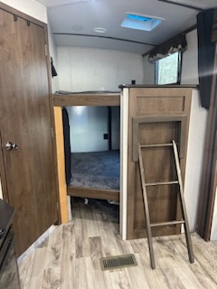 Spacious RV rental bunkhouse interior. Features wooden bunk beds, ladder, and stylish flooring, ideal for family travel.. Keystone Cougar 2020
