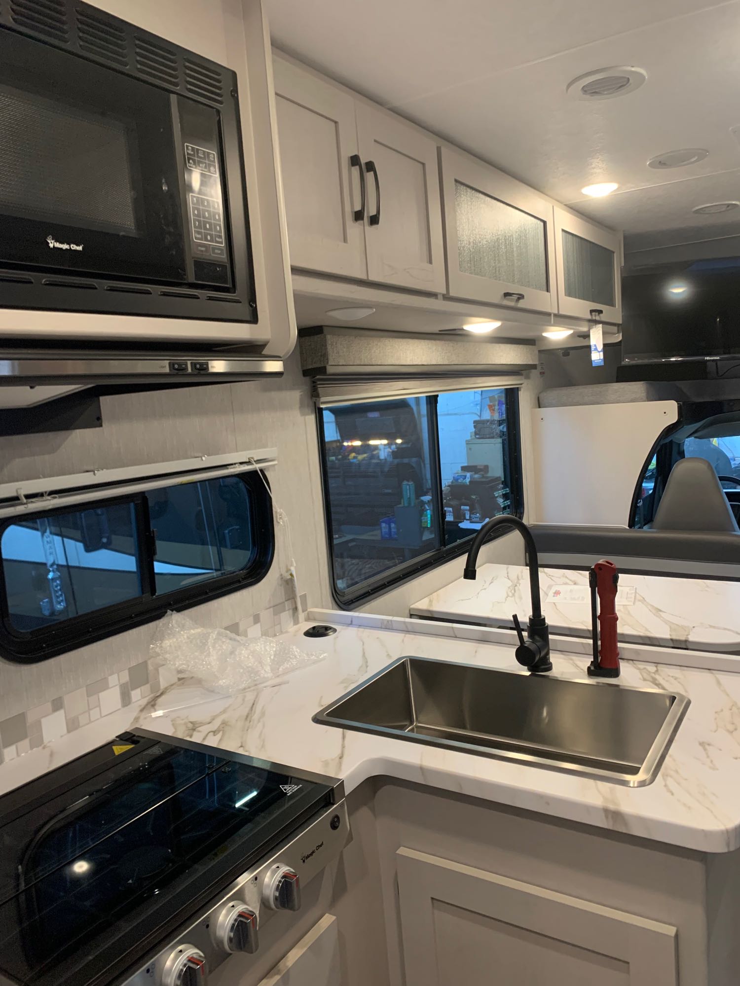 This RV rental features a modern kitchen setup with a microwave, stove, sink, and ample storage cabinets.. Coachmen Freelander 2023