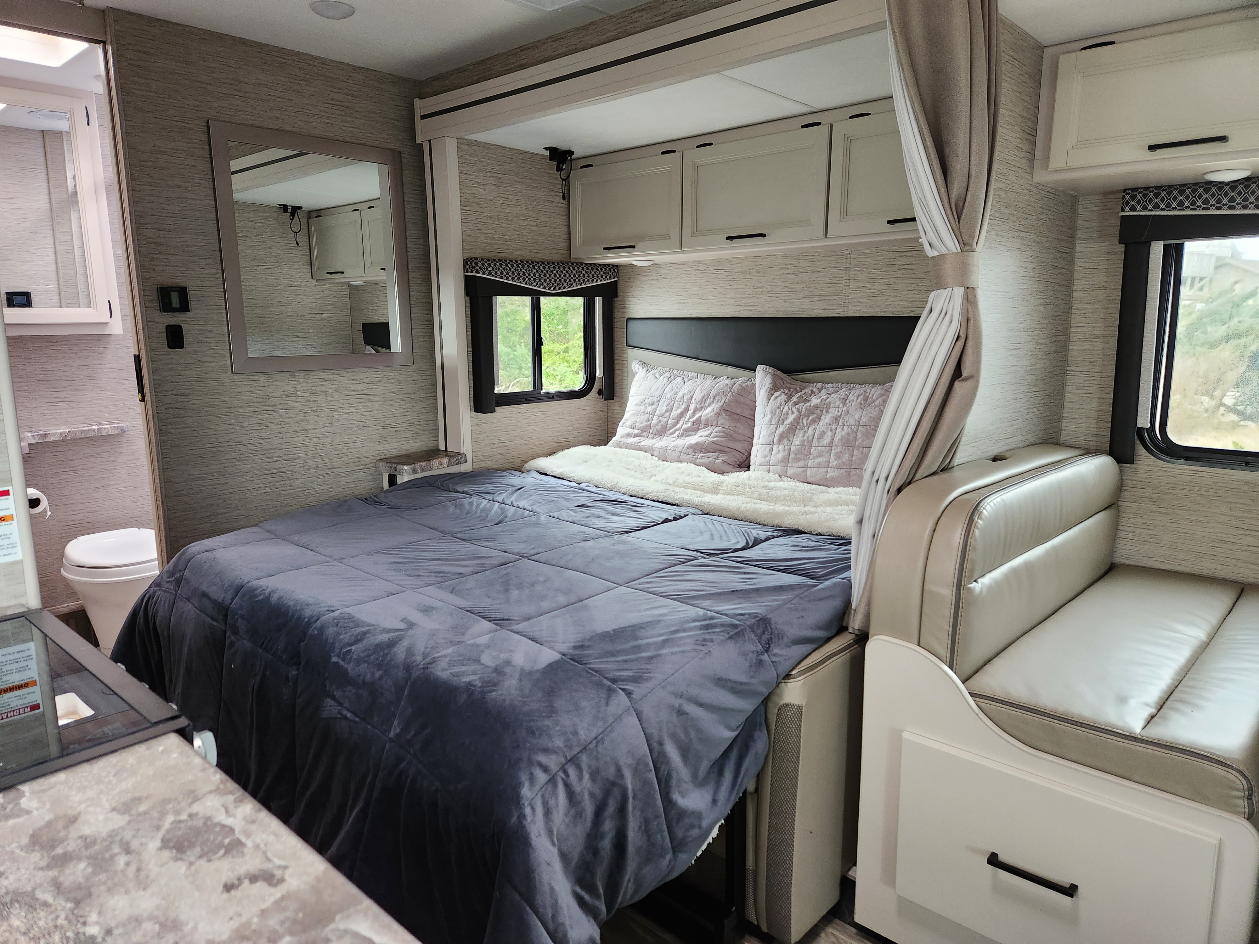Well-appointed RV rental interior showcasing a bedroom, bathroom access, and a comfortable dinette.. Thor Motor Coach Four Winds 2023