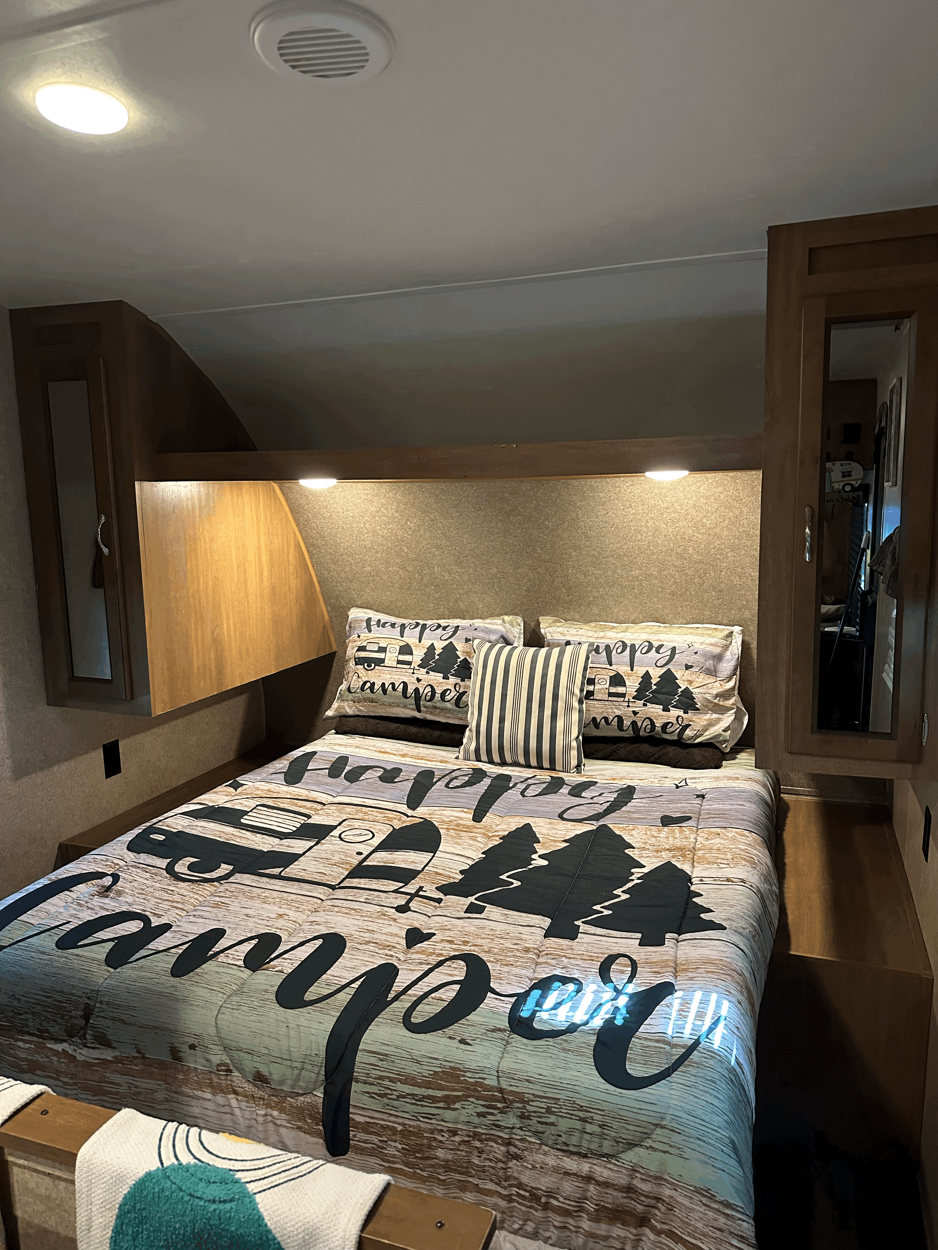 Cozy RV rental bedroom featuring "Happy Camper" themed bedding and built-in storage, ideal for a comfortable stay.. Coachmen Other 2017