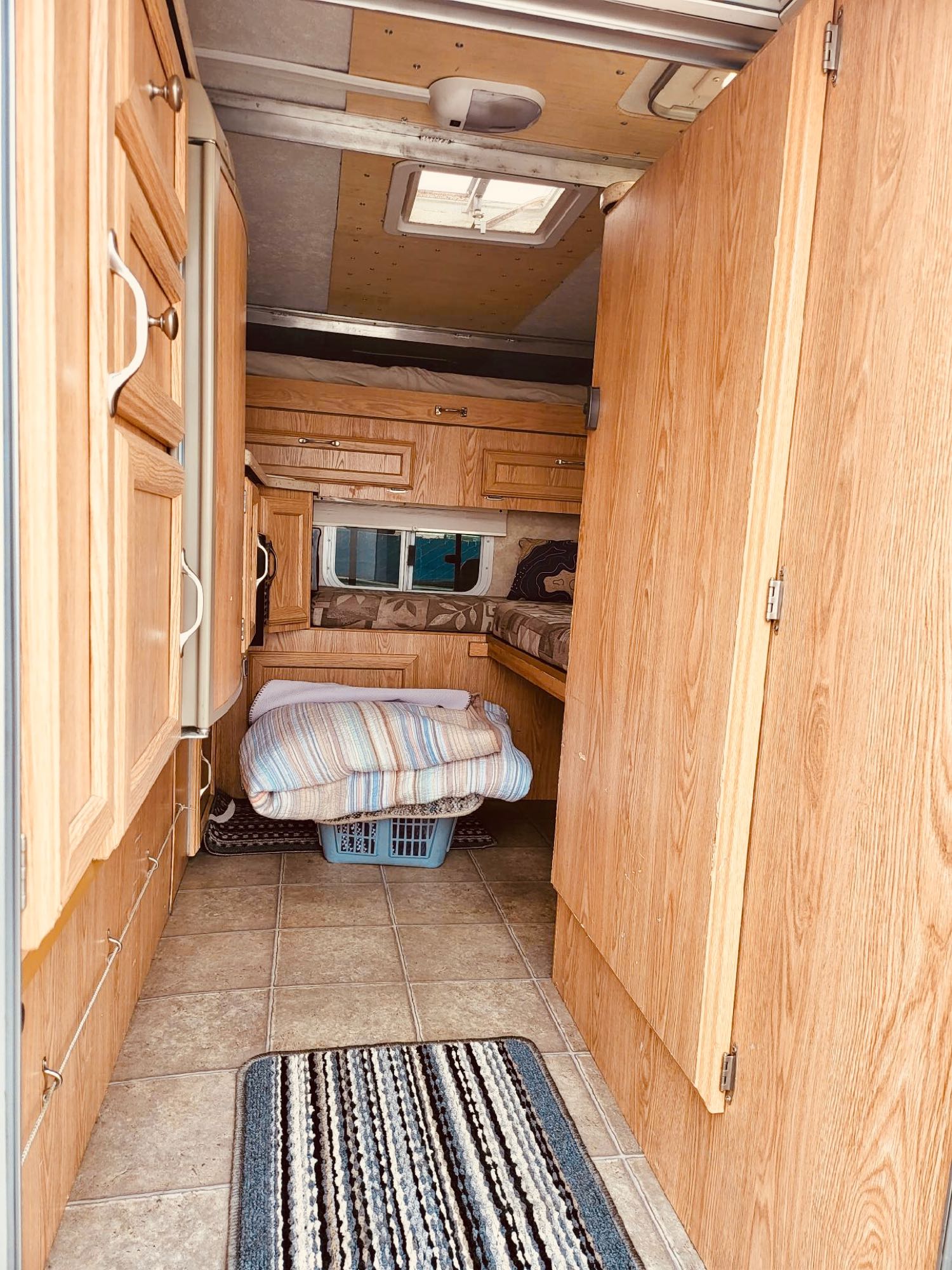 Inside an RV rental: a cozy space with light wood cabinetry, tiled floor, and a bed area visible in the rear.. Ford F350 Diesel Double Cab 2004