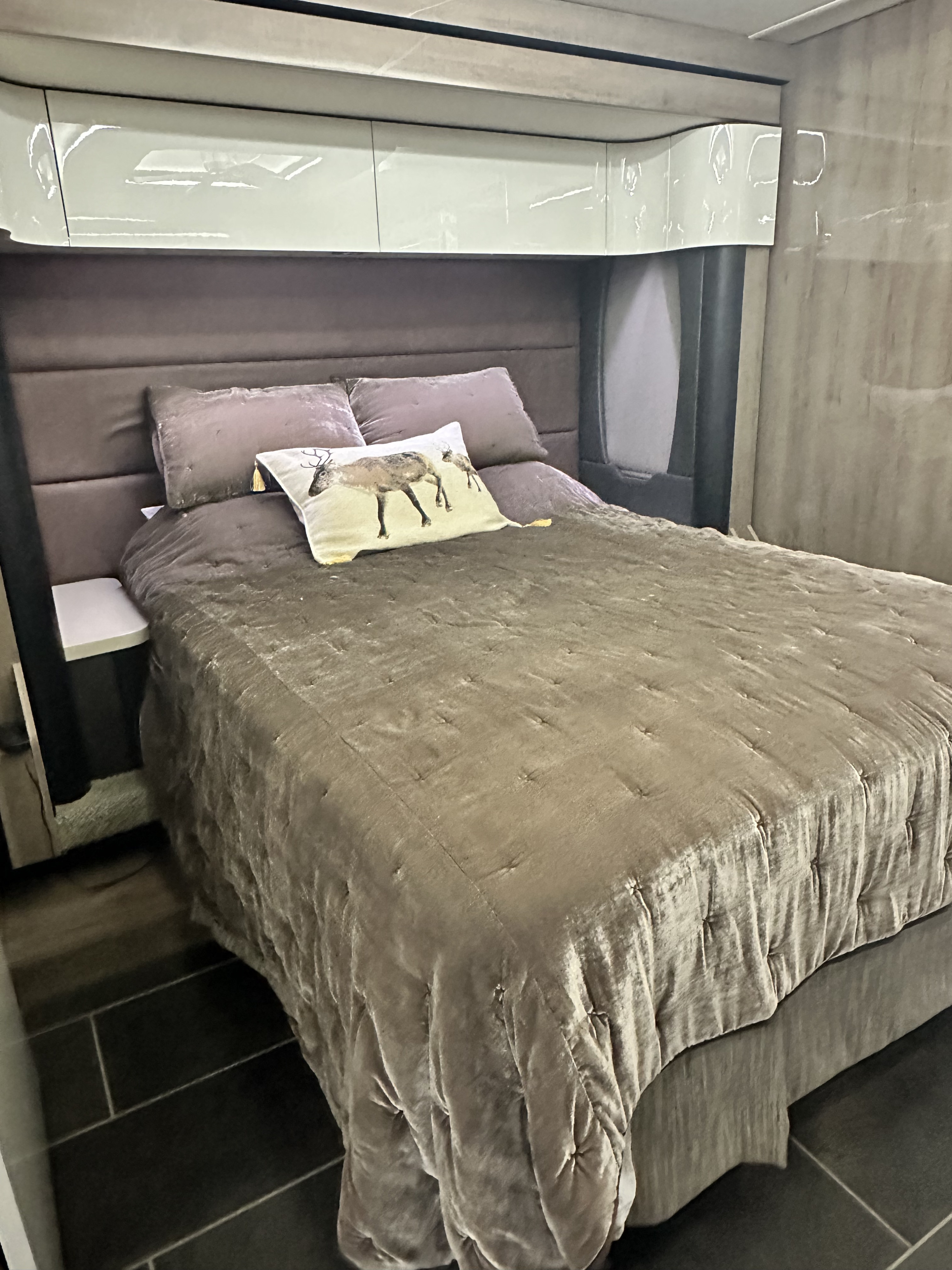 Experience comfort in this RV rental bedroom with a velvet bedspread, upholstered headboard, and sleek overhead storage.. Winnebago Horizon 2020