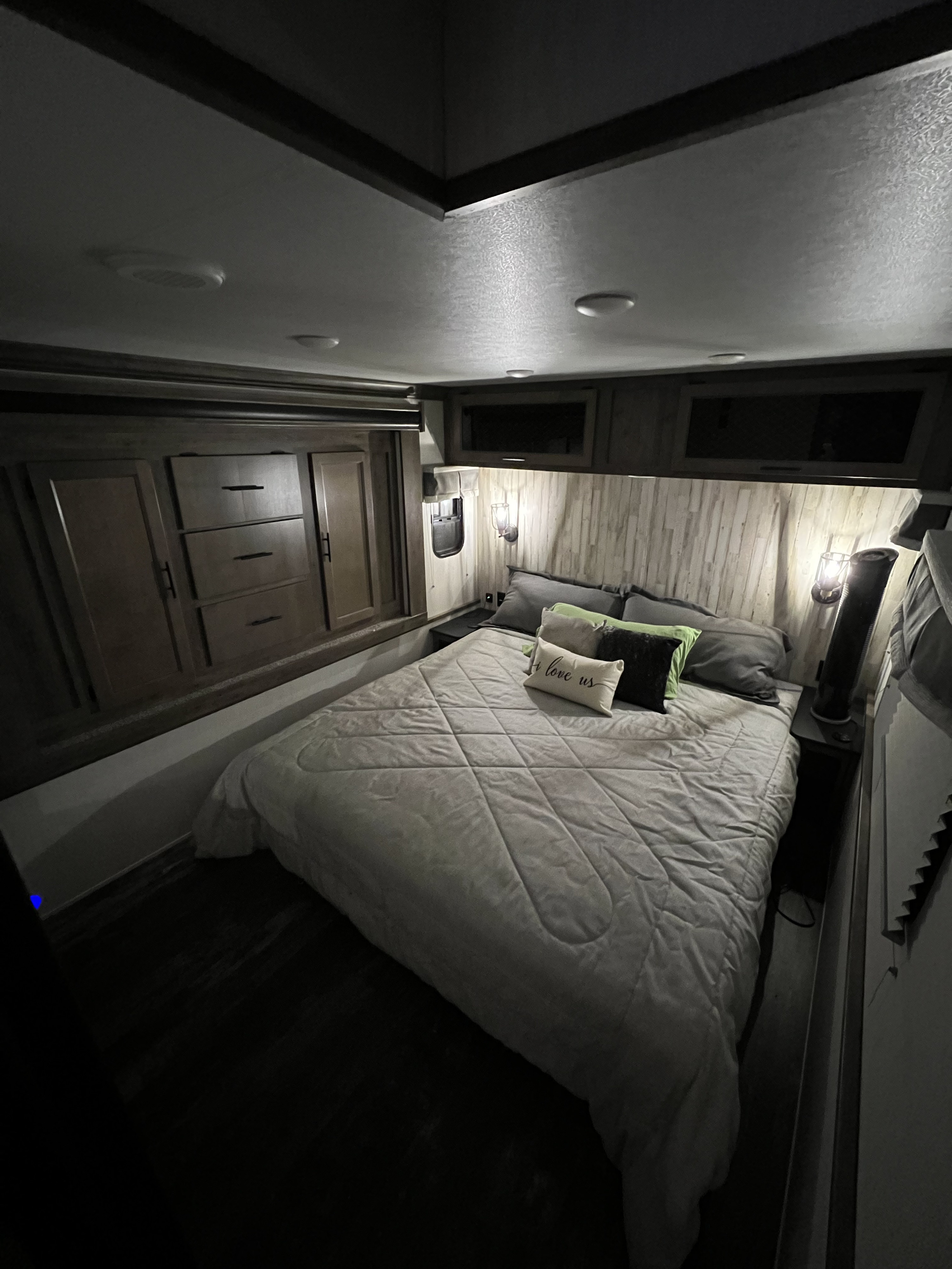 Discover comfort in this RV rental bedroom: a plush bed, rustic headboard, and built-in storage provide a cozy retreat.. Forest River Sabre 2021