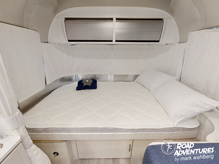 RV rental bedroom with a comfy white bed, privacy shades, and under-bed storage, ready for your road adventures.. Airstream Bambi 22FB 2023
