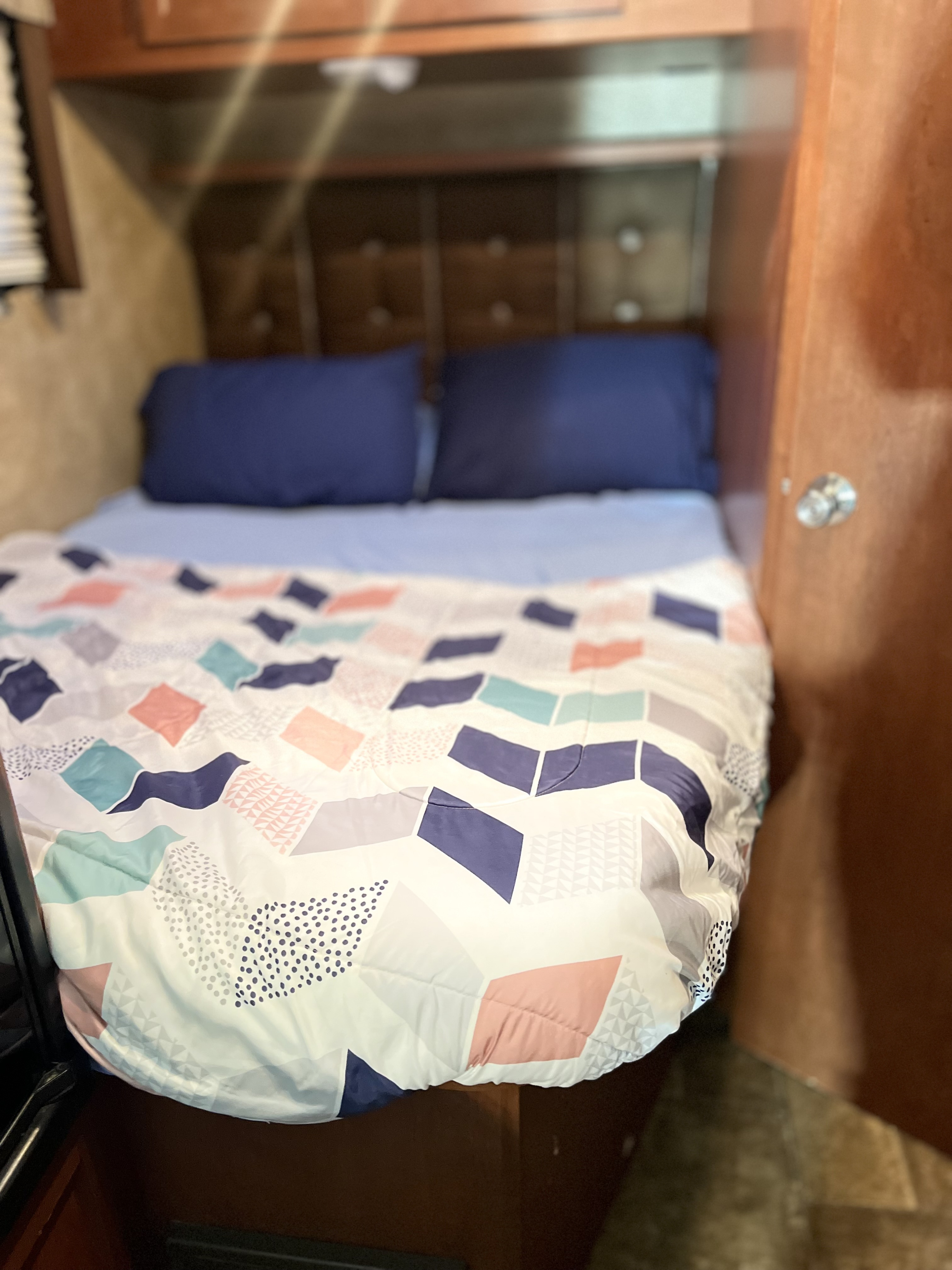 This RV rental features a compact, comfortable bedroom with a stylish patterned comforter and navy pillows.. Winnebago Minnie Winnie 2015