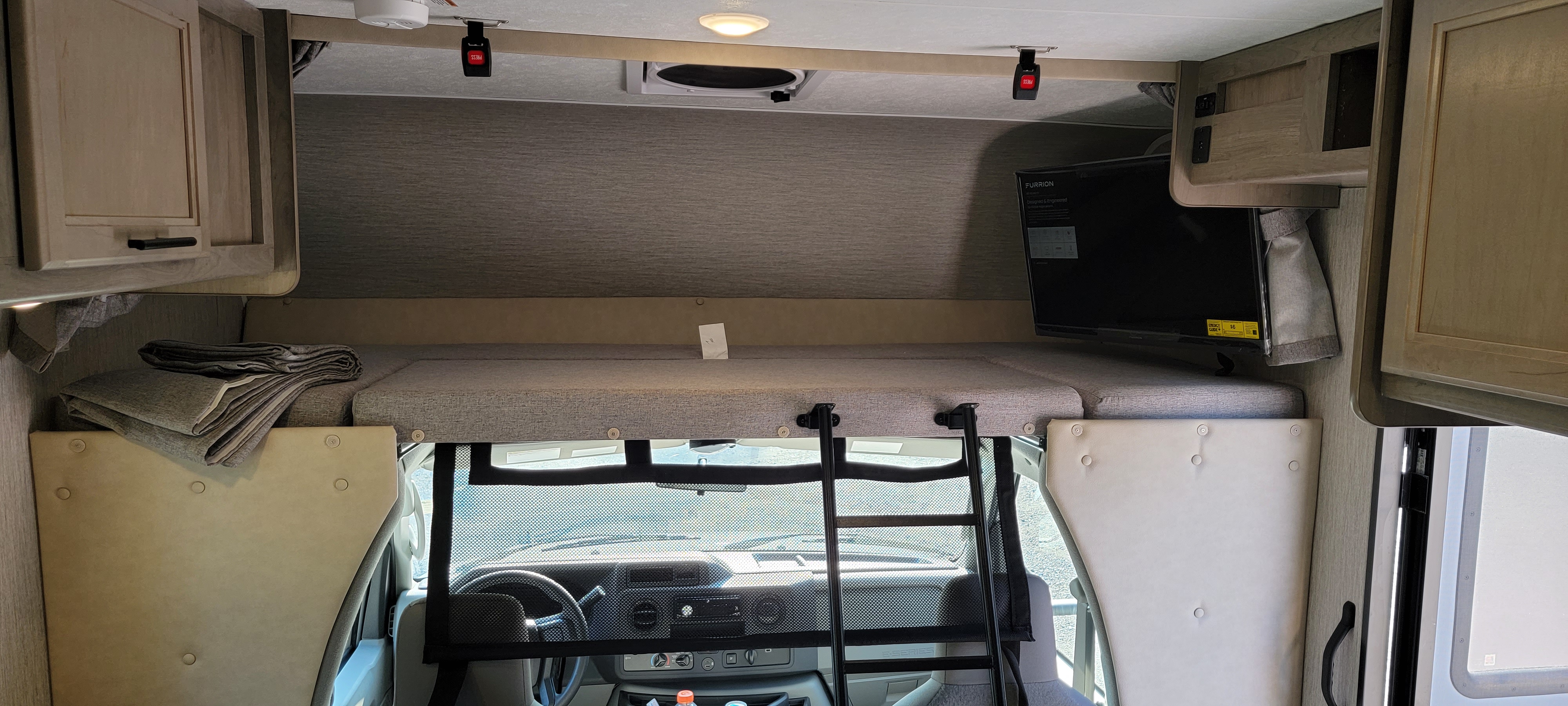 Inside this spacious RV rental, find a comfortable cab-over bunk with a TV, access ladder, and overhead cabinets.. Coachmen CrossTrek 2021