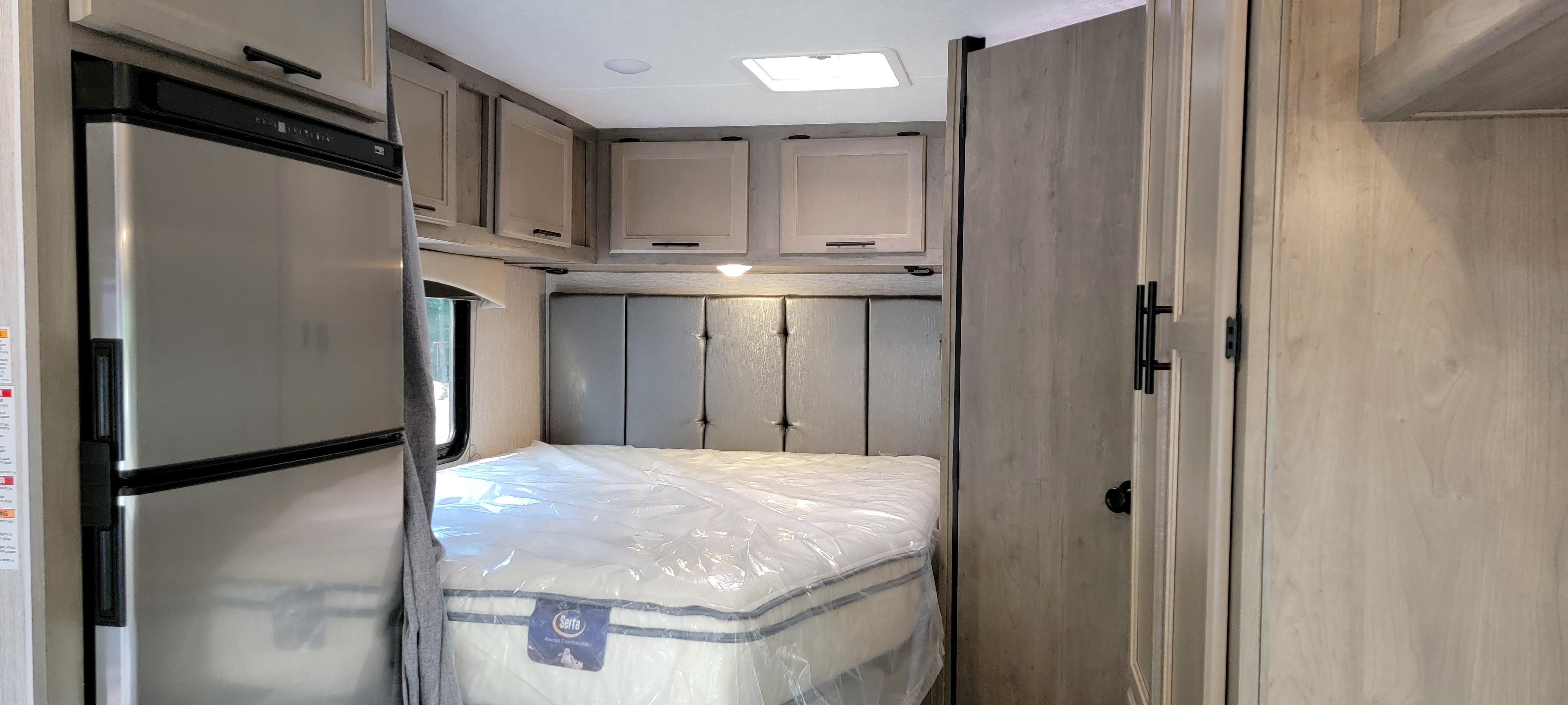 RV rental interior featuring a cozy bedroom with a new Serta mattress, fridge, & light wood cabinets.. Coachmen CrossTrek 2021