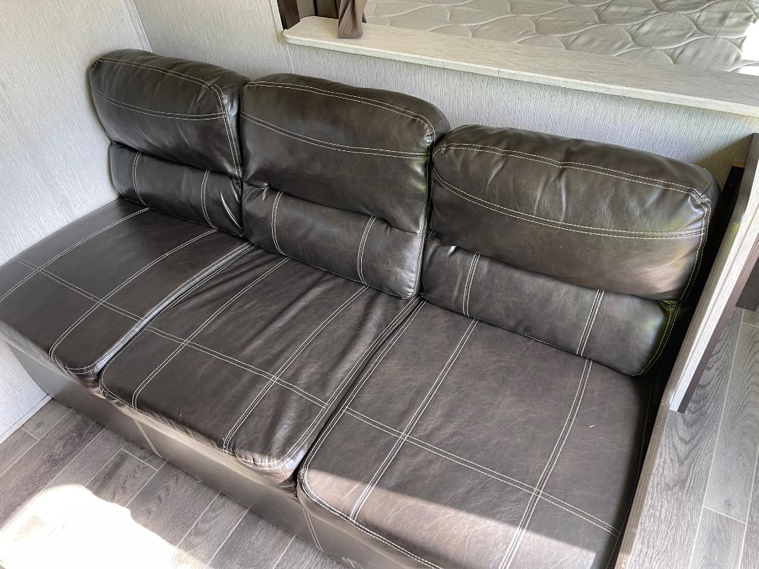 Relax on this dark brown faux leather sofa in your RV rental, featuring stylish white stitching.. Heartland RVs Trail Runner SLE 2019