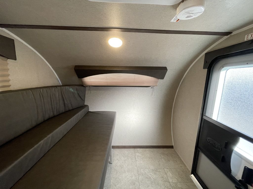 RV rental interior: dark gray convertible seating/bed, exit door, ceiling light, & smoke detector. Practical living space.. Sunset Park RV SunRay 2020