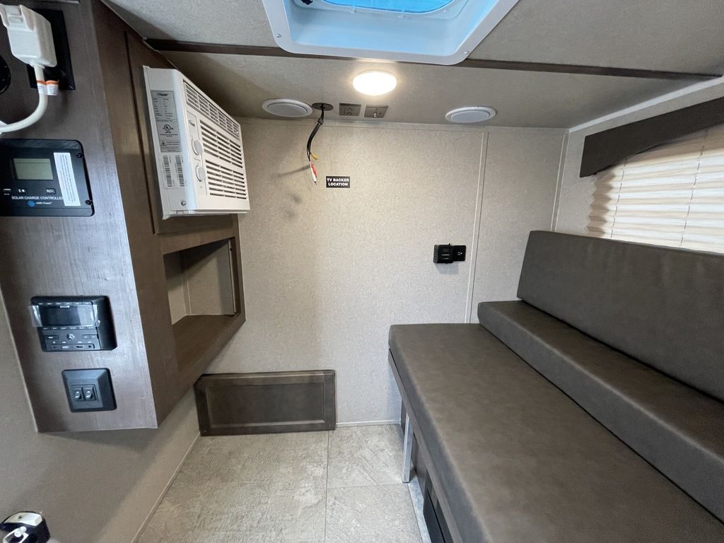 View of an RV rental's cozy interior, featuring a convertible bunk, wall AC, and solar charge controller.. Sunset Park RV SunRay 2020