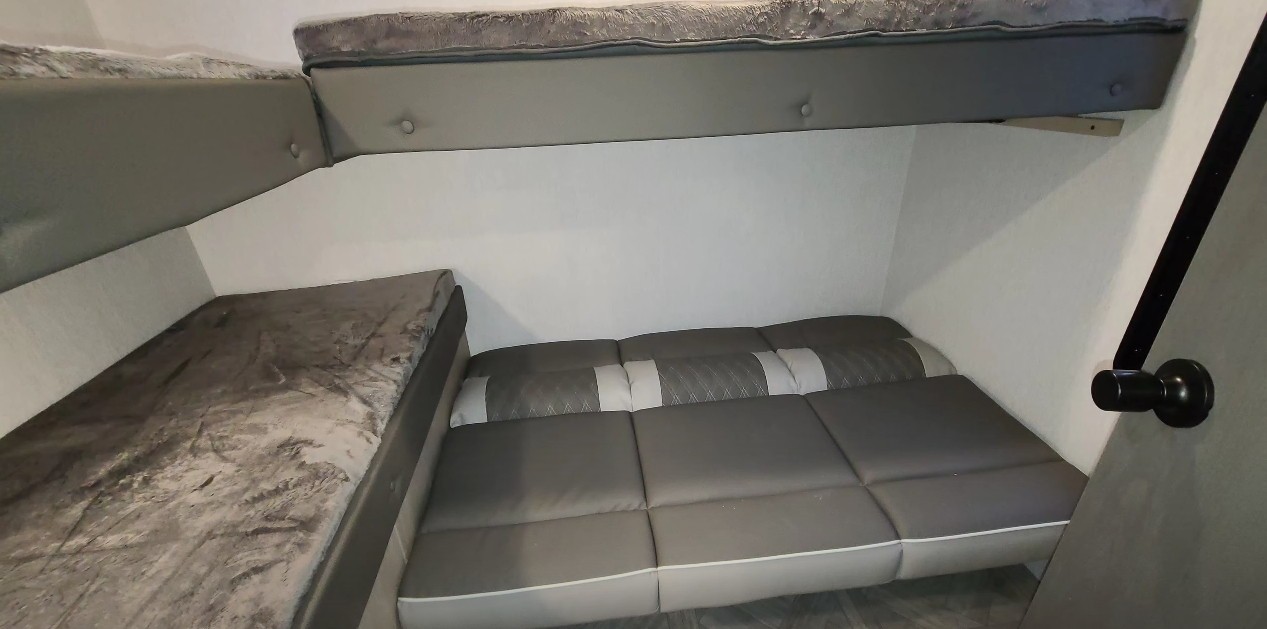 RV rental bunk beds: a top bed with a grey mattress, and a lower bed made of segmented grey cushions.. Forest River Other 2023