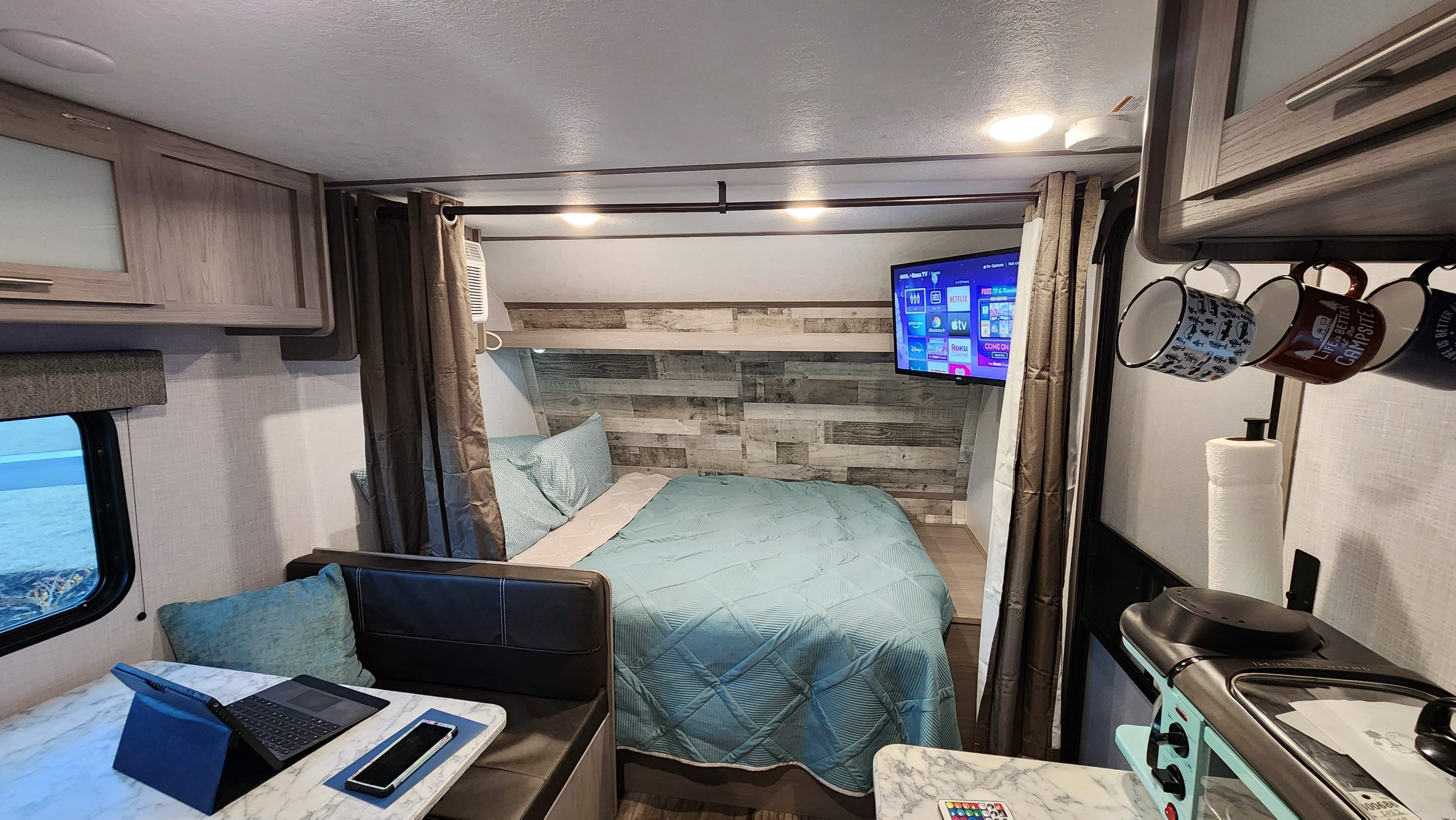 Cozy RV rental interior: A compact space with a bed, dinette, kitchen, and TV, perfect for travel and camping adventures.. Coleman Lantern 2023