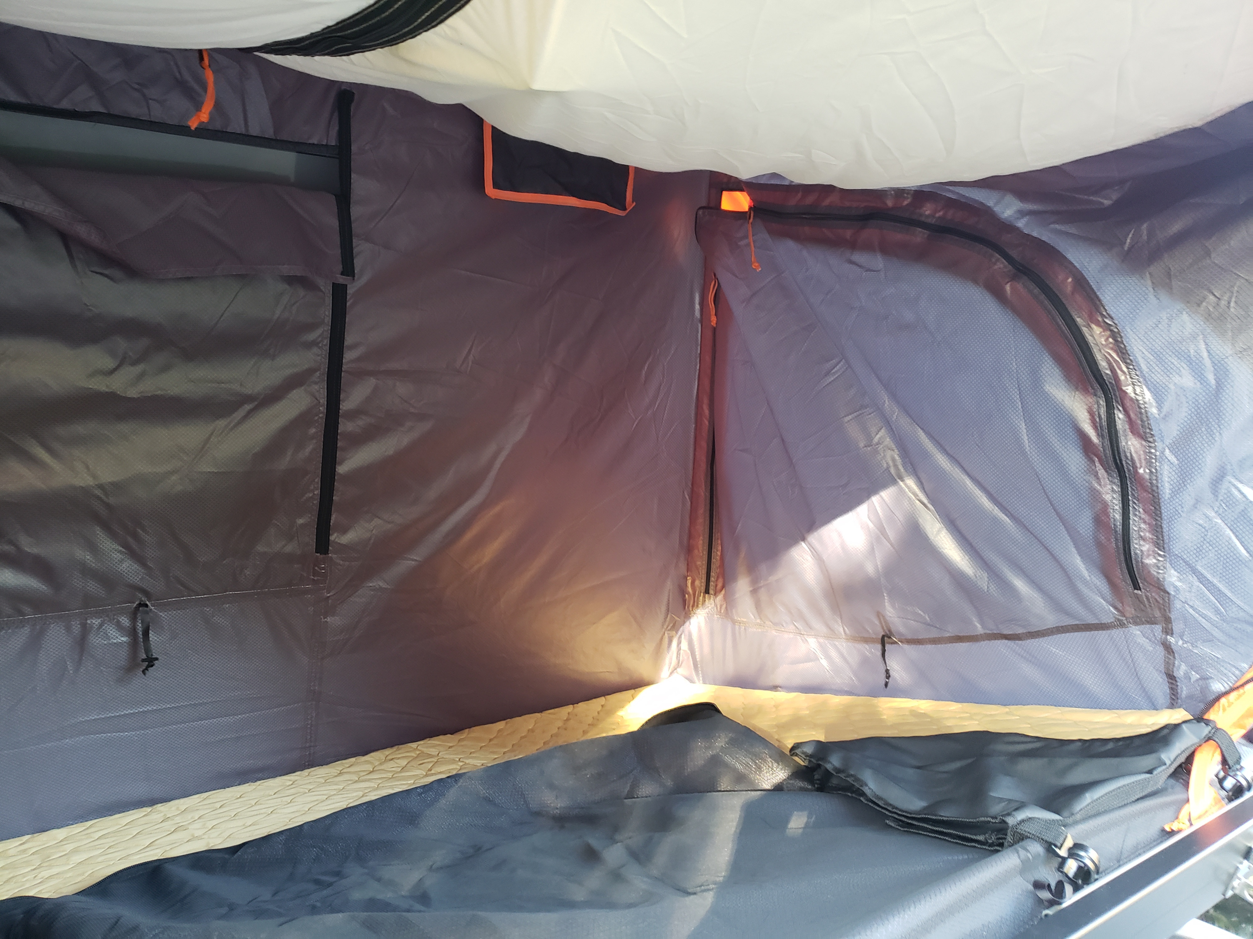 Inside a cozy RV rental tent: a comfortable sleeping area with light filtering through the mesh window.. Nissan Other 2011