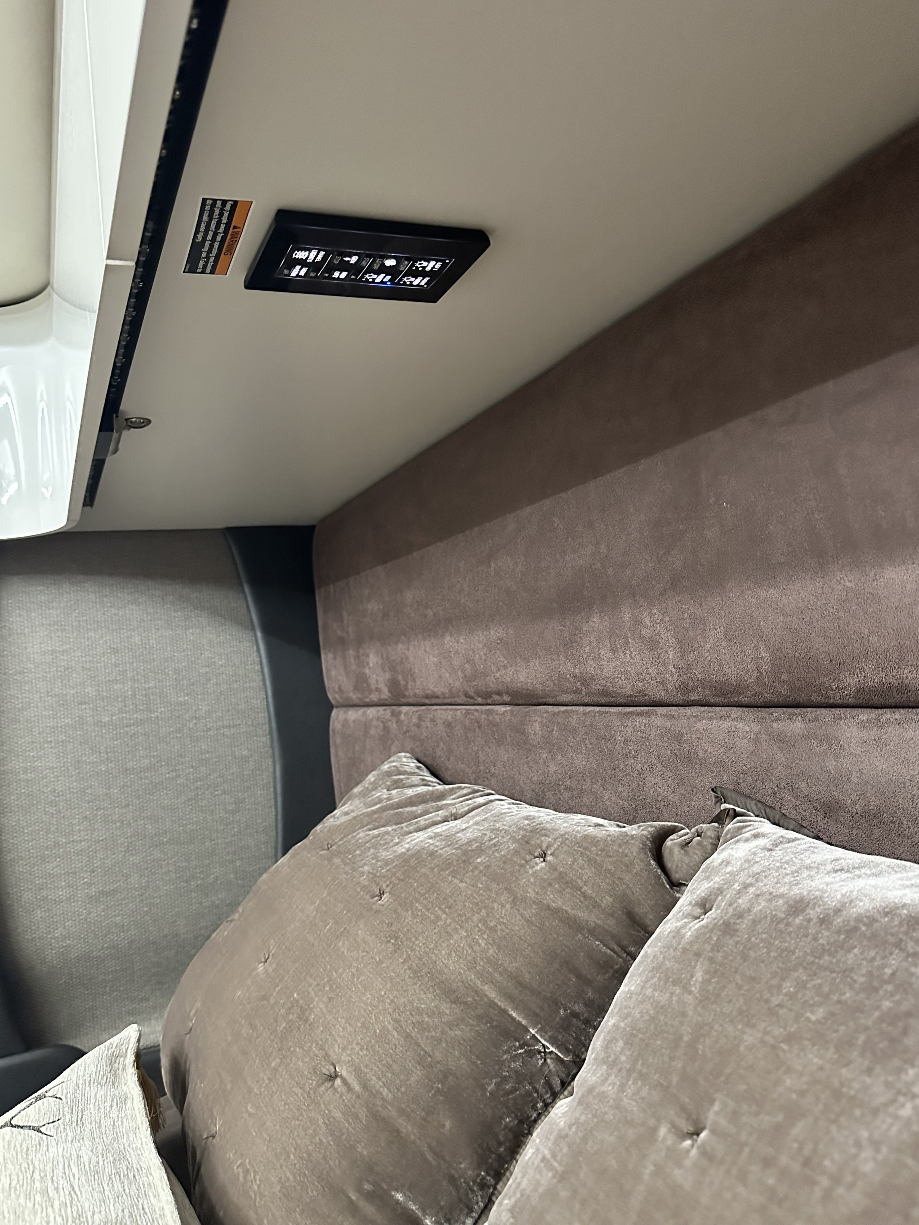 RV rental: Bedside control panel for lights/functions in a cozy interior, with a visible warning for pinch hazards.. Winnebago Horizon 2020