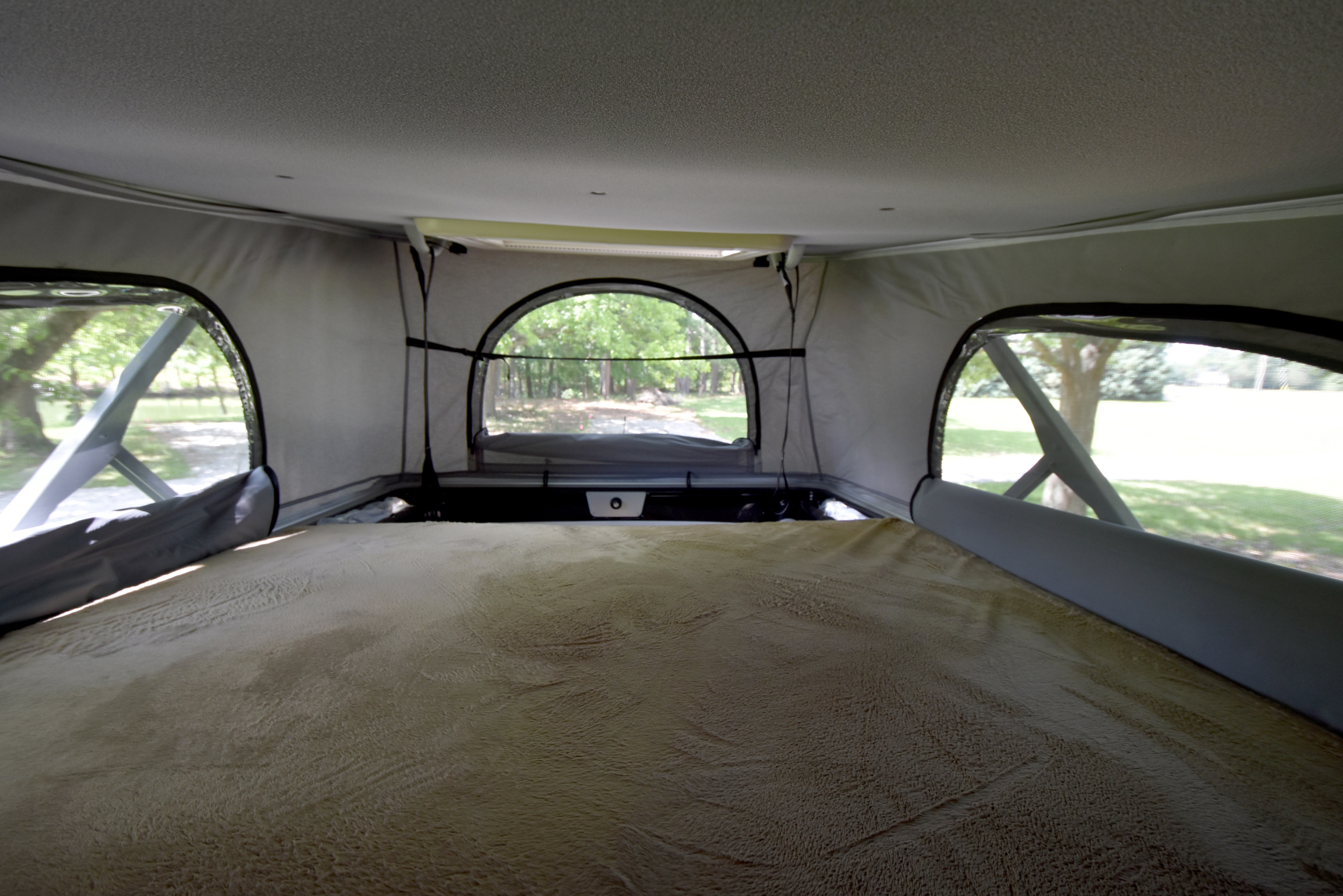 Cozy pop-top bed in an RV rental, offering serene views through mesh windows. Ideal for nature lovers.. Thor Motor Coach Scope #9173 2023