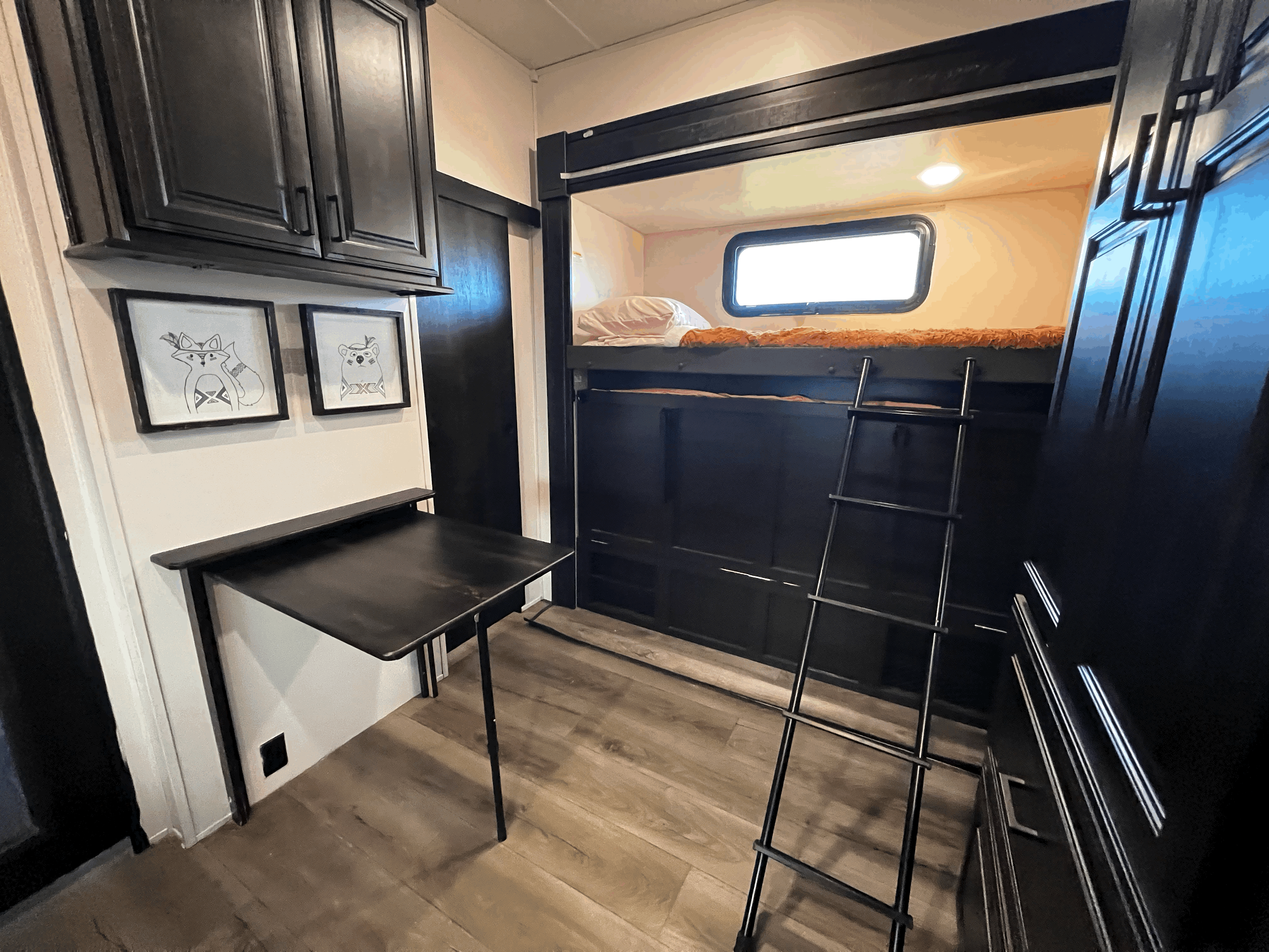 This RV rental interior features cozy bunk beds, a handy fold-down desk, and framed animal art for a functional space.. Highland Ridge RV Silverstar 2021