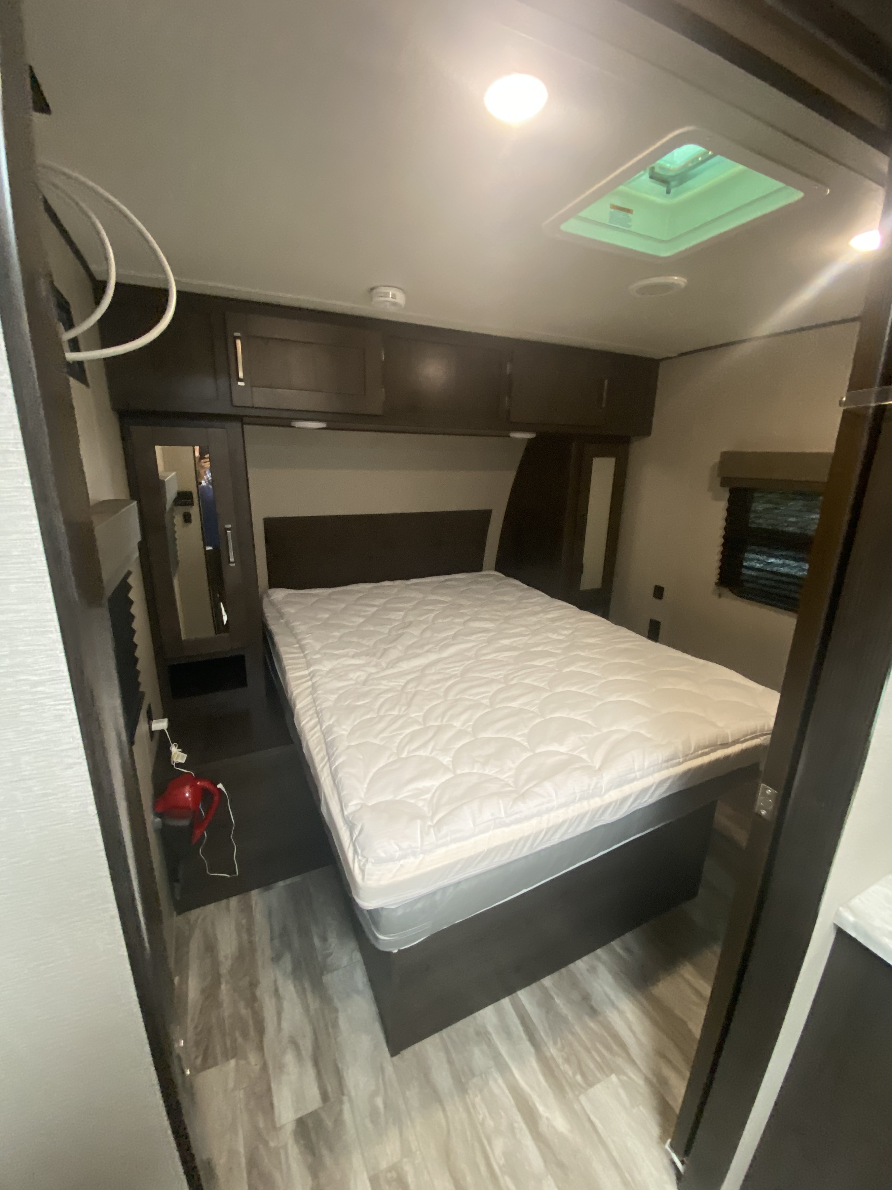 Spacious RV rental bedroom featuring a queen bed, ample storage, and skylight for comfortable travel.. Grand Design Transcend 2020
