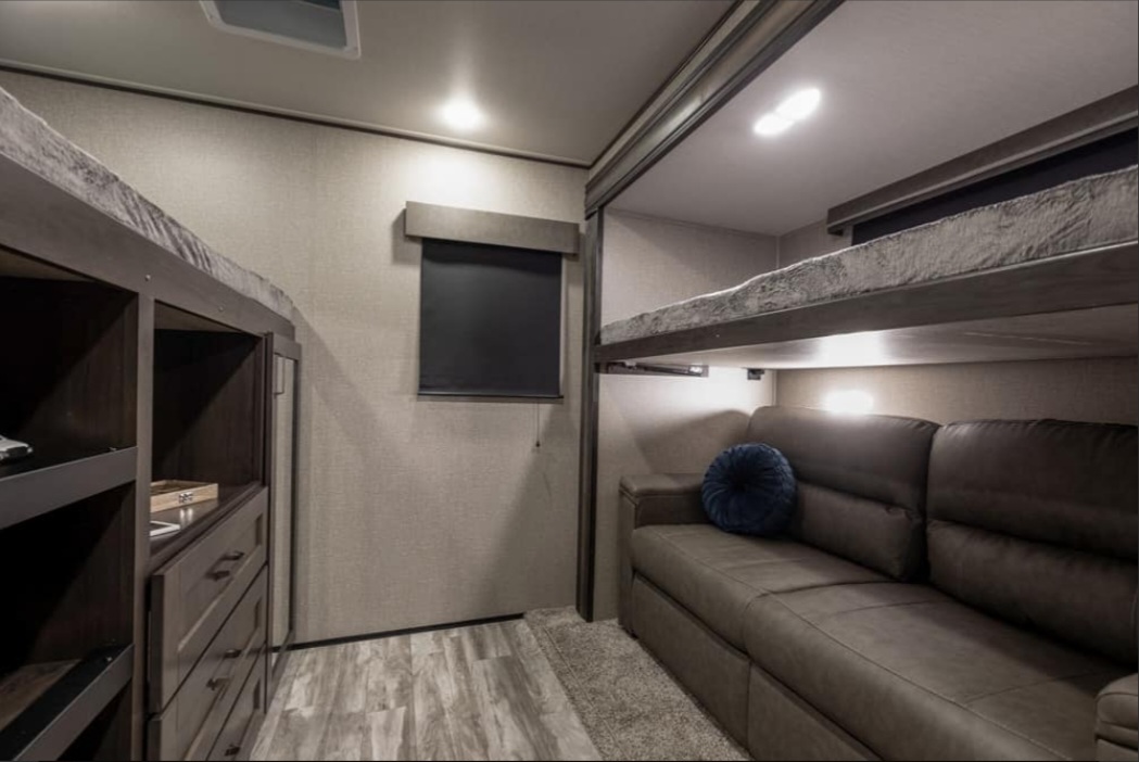 Inside a modern RV rental, featuring bunk beds, a comfy sofa, and smart storage.. Grand Design Reflection 2022