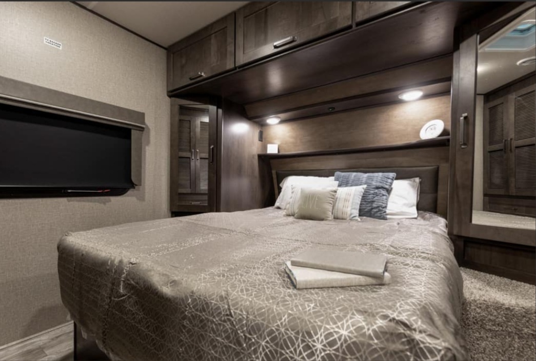 Comfortable RV rental bedroom featuring a large bed, wall-mounted TV, and ample storage cabinets.. Grand Design Reflection 2022