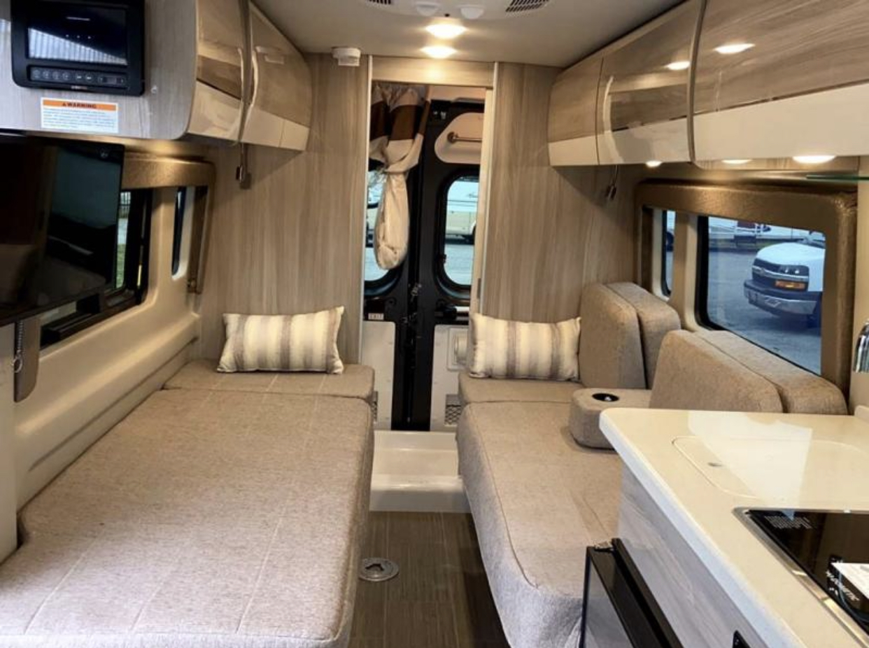 RV rental interior: cozy space featuring two versatile seating/sleeping areas, a compact kitchen, and overhead storage.. Thor Sequence 2021