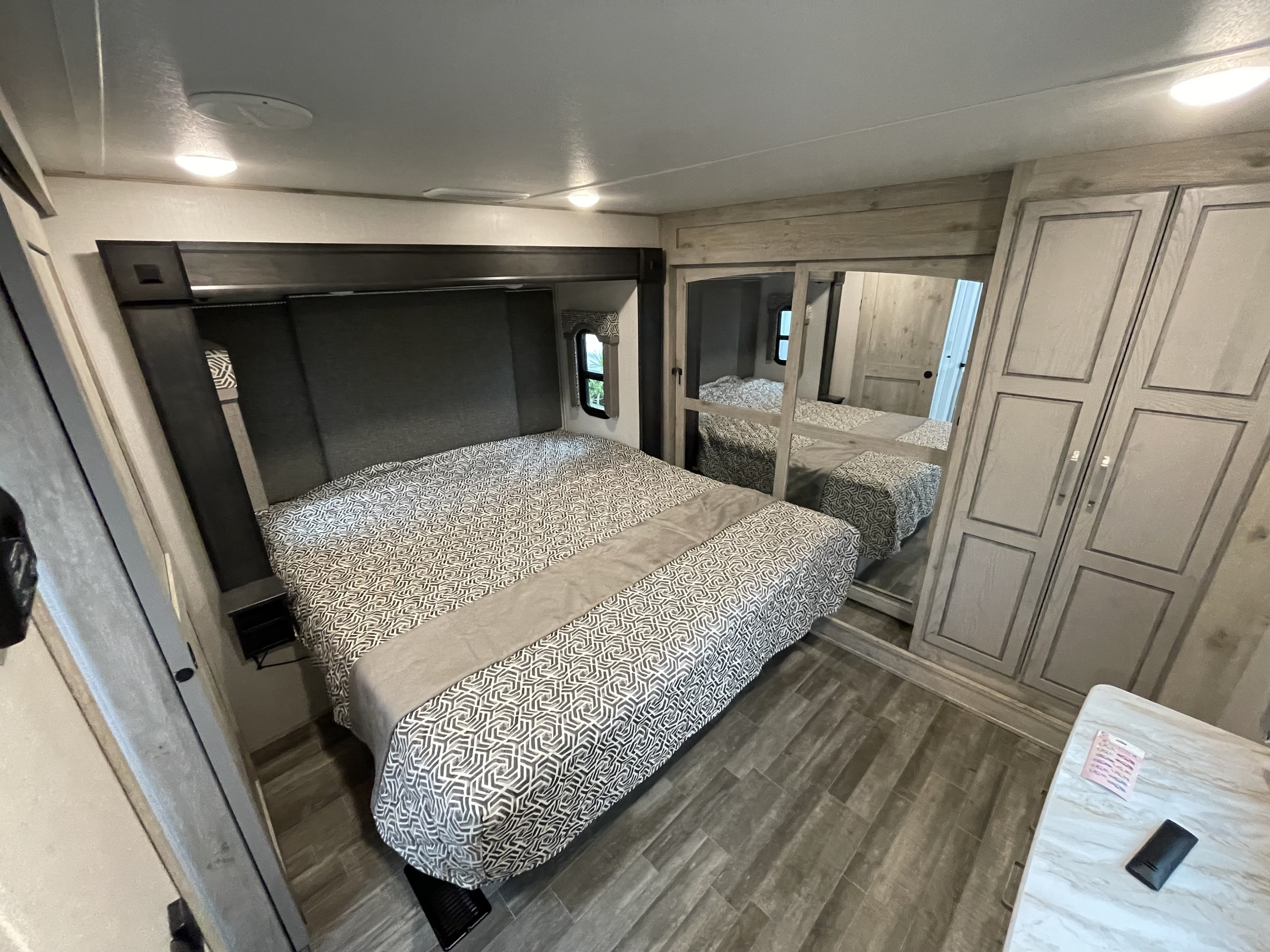 RV rental: A modern bedroom with a patterned bed, mirrored closet, and wood-look flooring.. Keystone RV Avalanche 2021