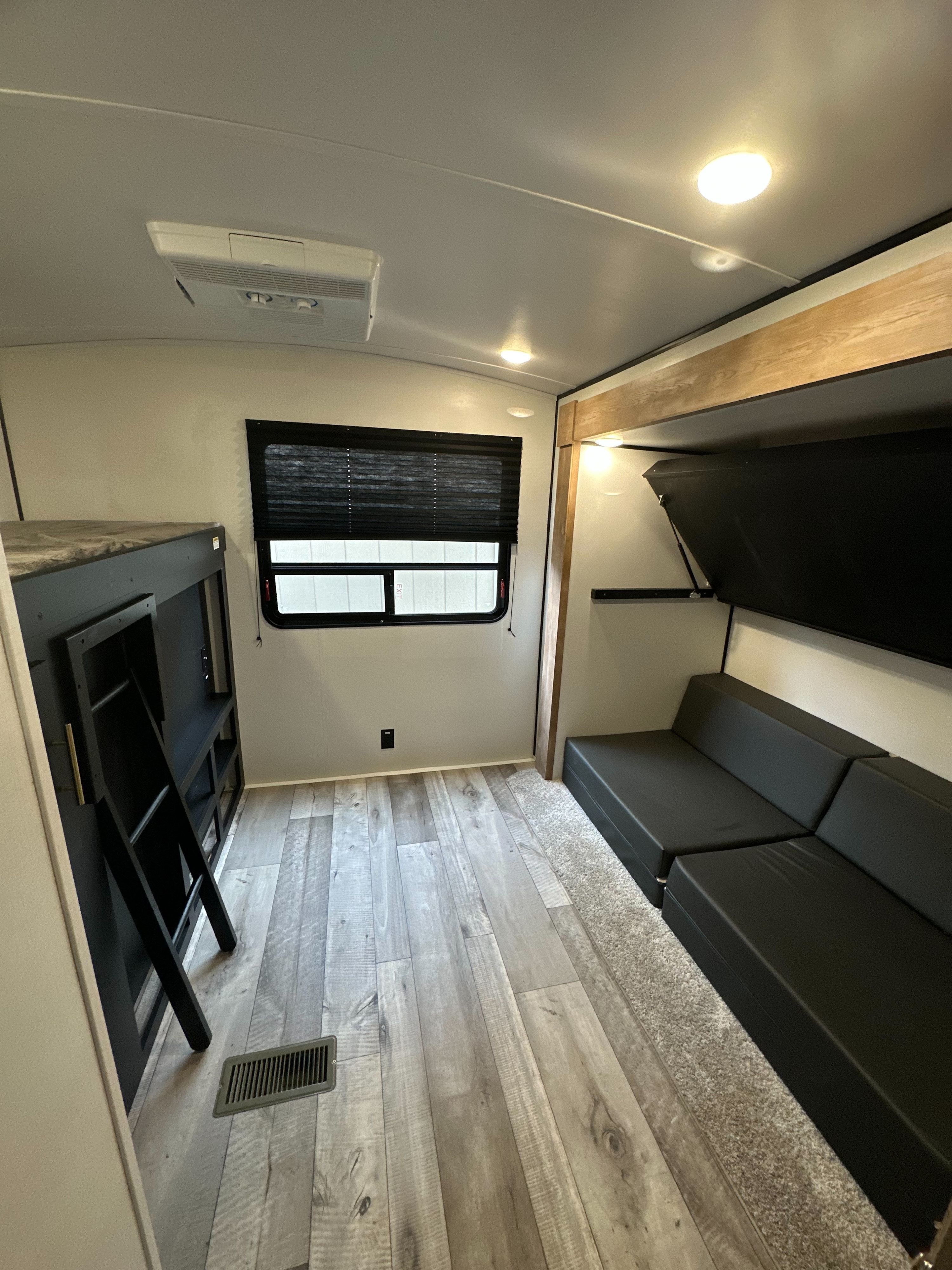 Modern RV rental interior with bunk beds, convertible sofa, wood-look floor, and AC. Great for family trips.. Keystone RV Springdale 2022