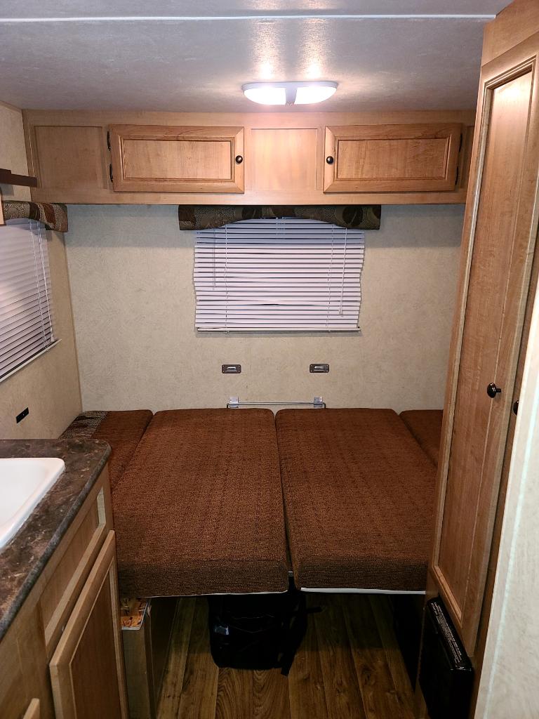 RV rental interior: convertible dinette/beds with brown cushions, wood cabinets, blinds, and wood floor.. Nomad 173 2013