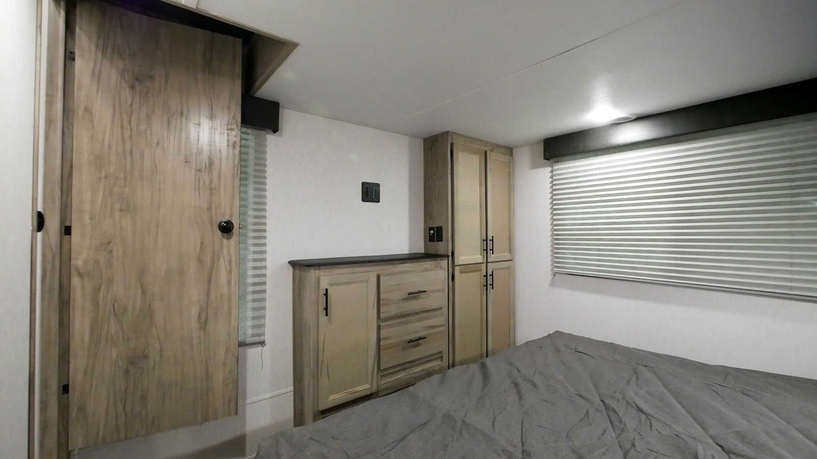 Compact RV rental bedroom featuring a bed, built-in cabinetry, and windows with blinds for comfort.. Forest River Cherokee Arctic Wolf 2022
