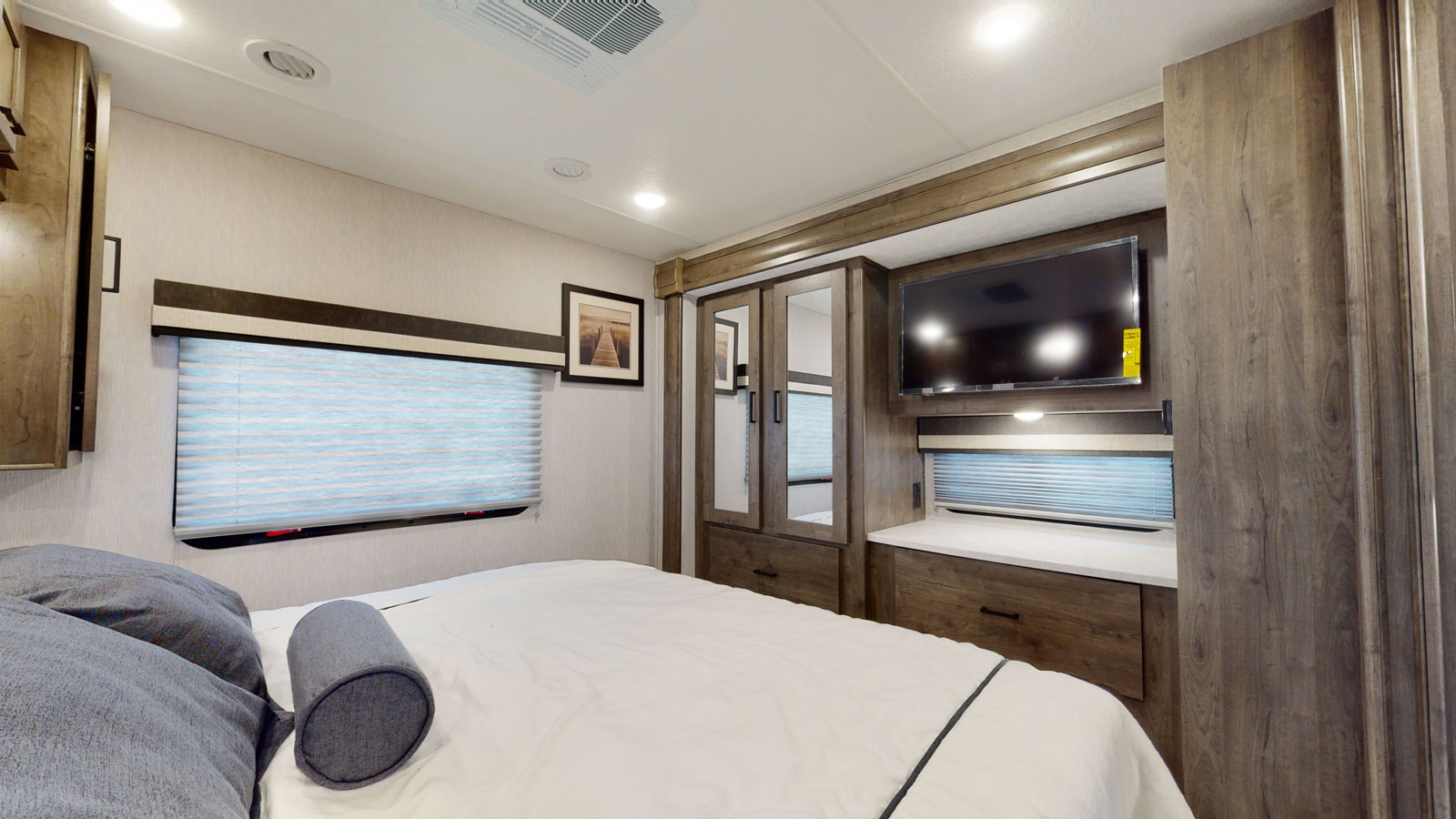Cozy RV rental bedroom with a comfortable bed, wall-mounted TV, and integrated wooden cabinets. Your perfect travel retreat.. Coachmen MIRADA 35ESF 2026