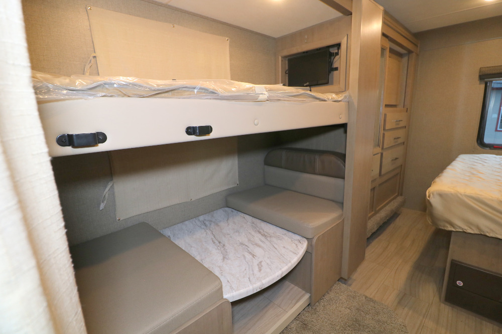 Spacious RV rental interior featuring bunk beds, a convertible dinette, TV, and a cozy bedroom area.. Thor Coleman 2021
