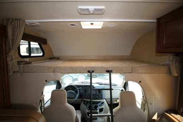 Interior of an RV rental, showcasing the cab-over bunk bed, driver's area, and ladder. Perfect for camper trips.. Thor Coleman 2021