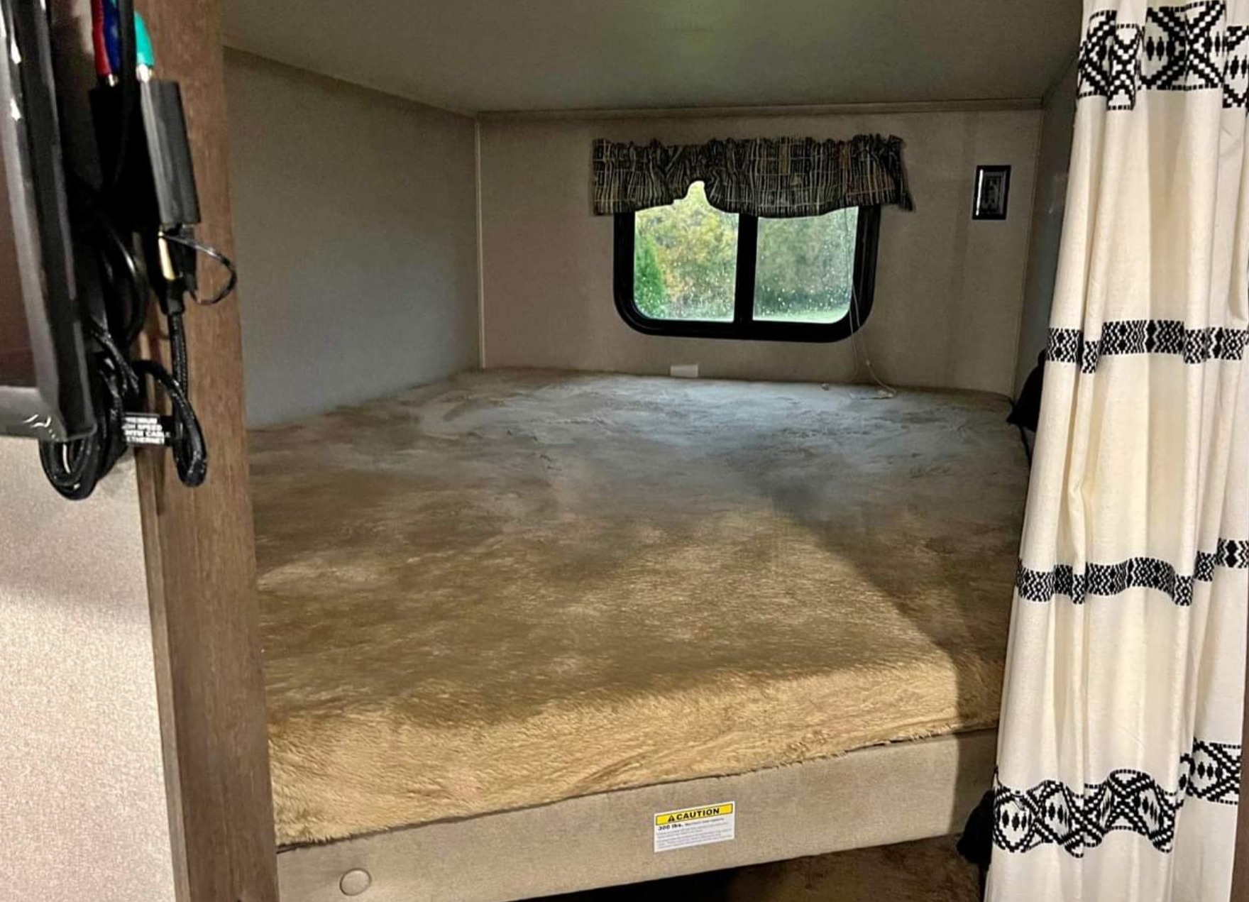 Inside an **rv rental**, a comfortable bunk bed with a plush, fuzzy mattress, window, and patterned curtain creates a cozy sleeping area.. Keystone RV Hideout LHS 2019