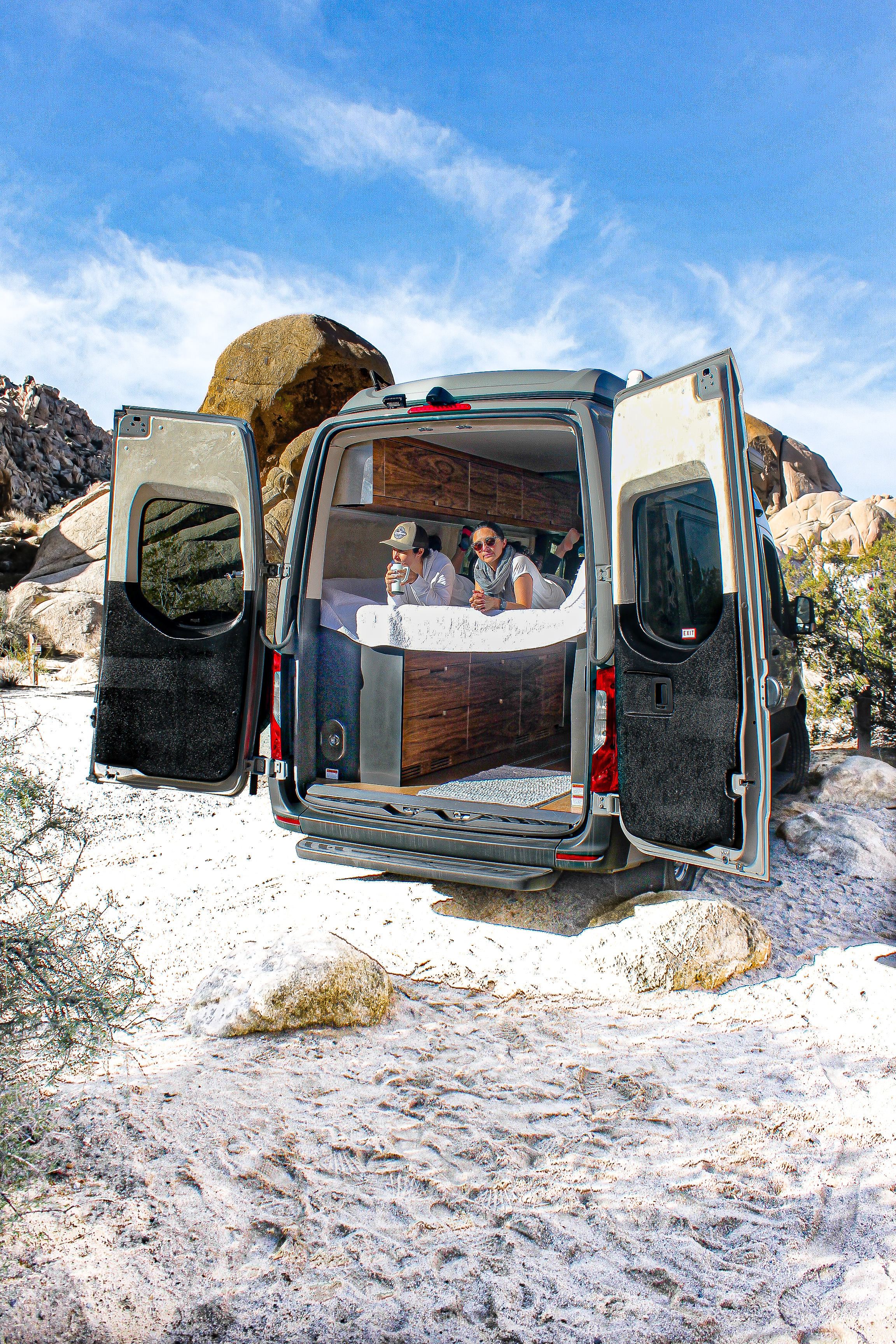Relax in comfort on your next RV rental adventure! Two people enjoy the desert view from their camper van bed.. Mercedes-Benz texino 2020
