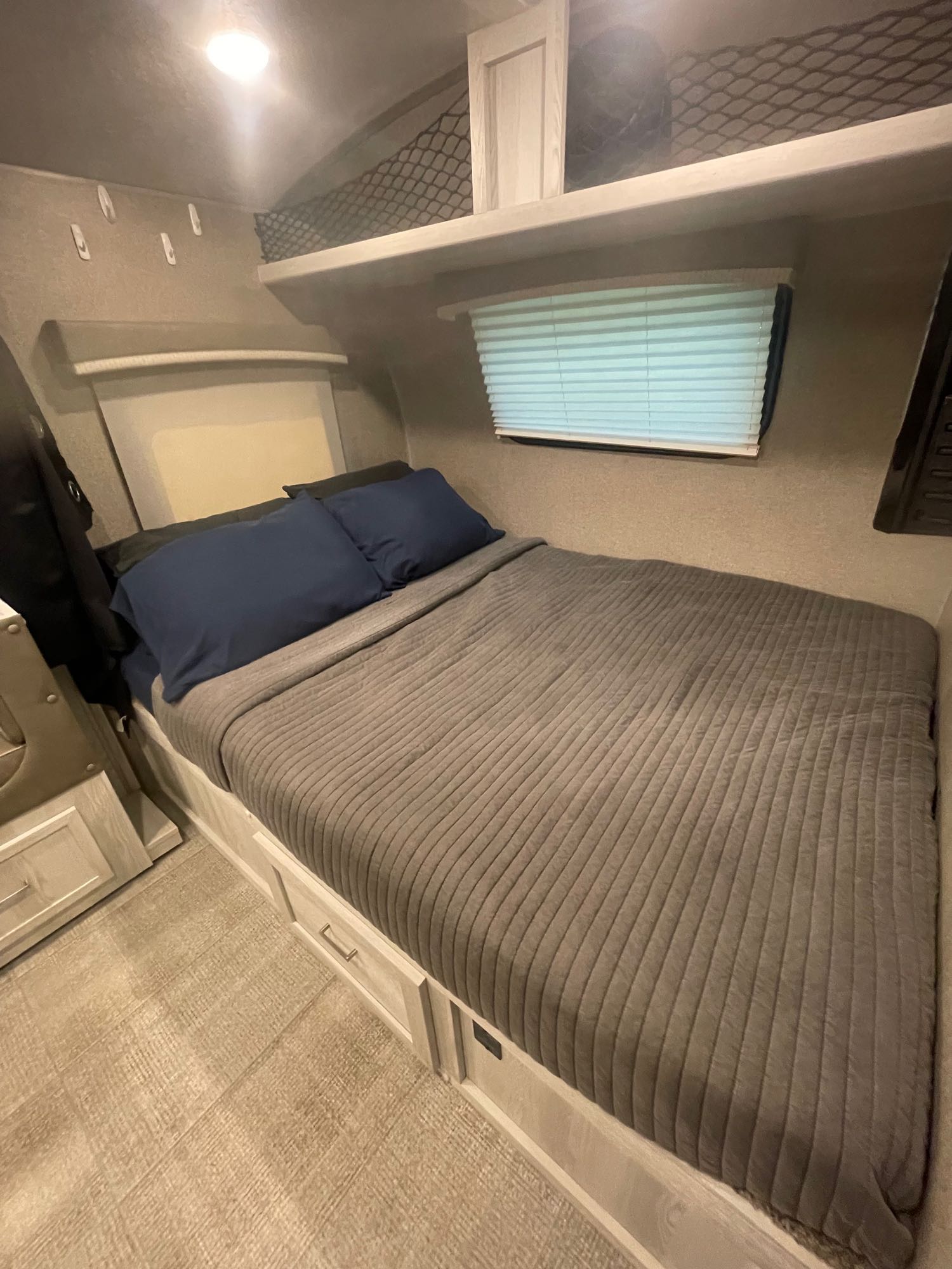 Cozy RV rental bedroom with a bed, under-bed storage, window blinds, and overhead netting for compact travel.. Forest River Rockwood Geo Pro 2021