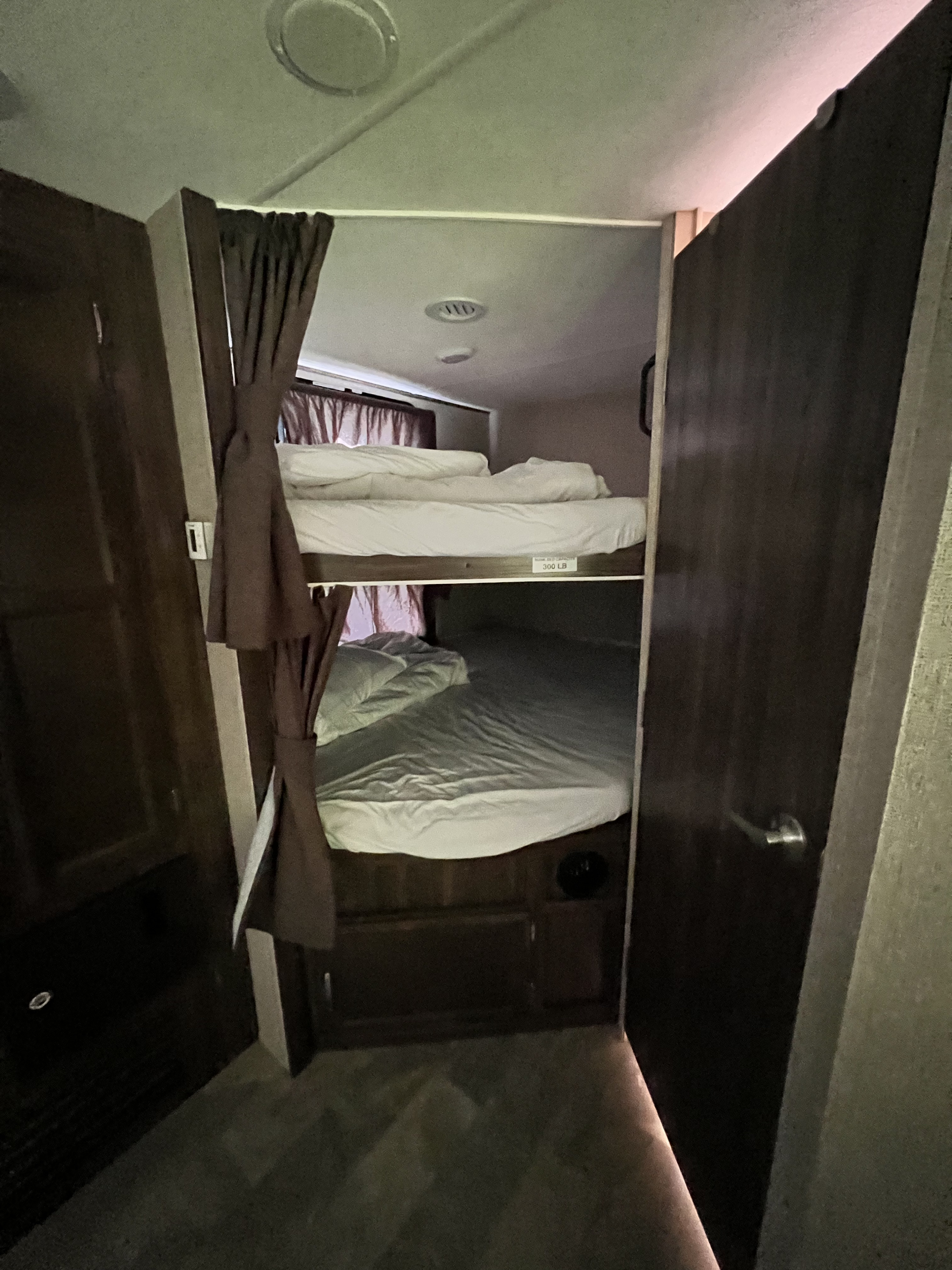 Cozy RV rental bunk beds, with curtains, offer a compact sleeping area. Perfect for a camper's functional interior.. Coachmen Apex 2018