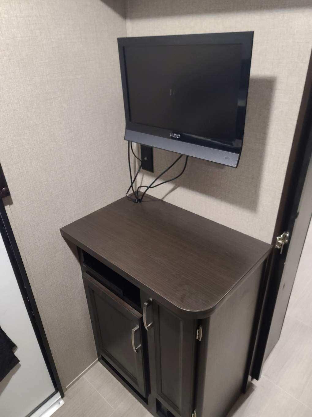 This RV rental offers a Vizio TV wall-mounted above a dark media cabinet, ideal for your travel entertainment needs.. Jayco Jay Feather 2022