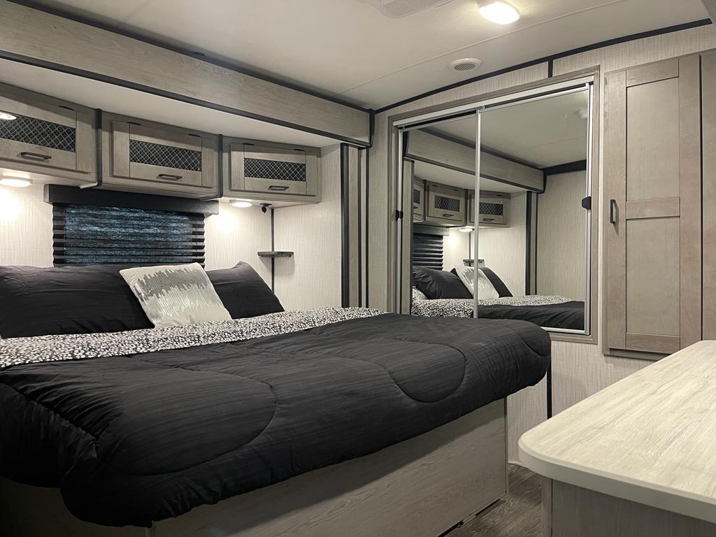Cozy RV rental bedroom with a large bed, overhead storage, and mirrored wardrobe. Ideal for travel.. Heartland Mallard 2021