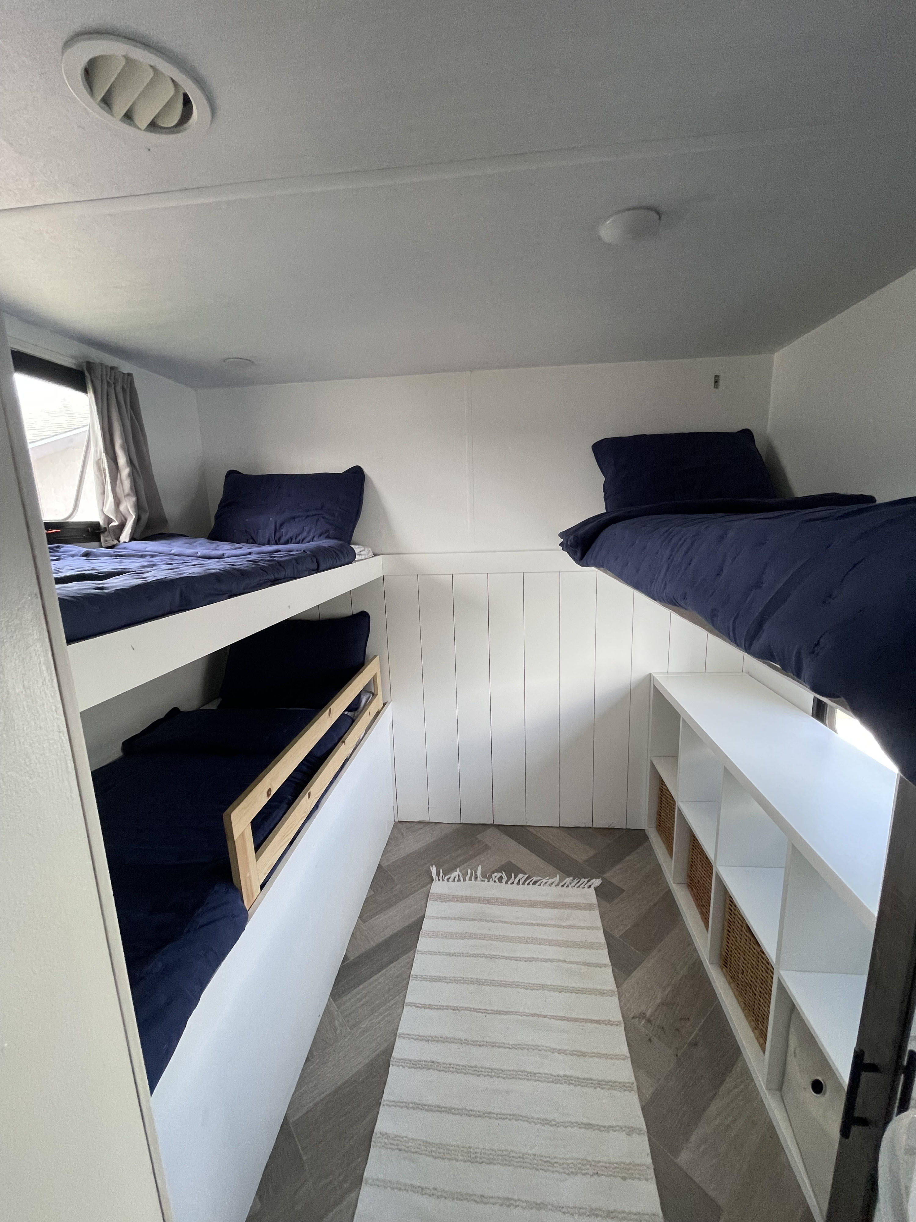 Spacious RV rental bunk room with cozy navy beds, built-in storage, and modern shiplap walls for a comfortable stay.. Forest River Salem 2021