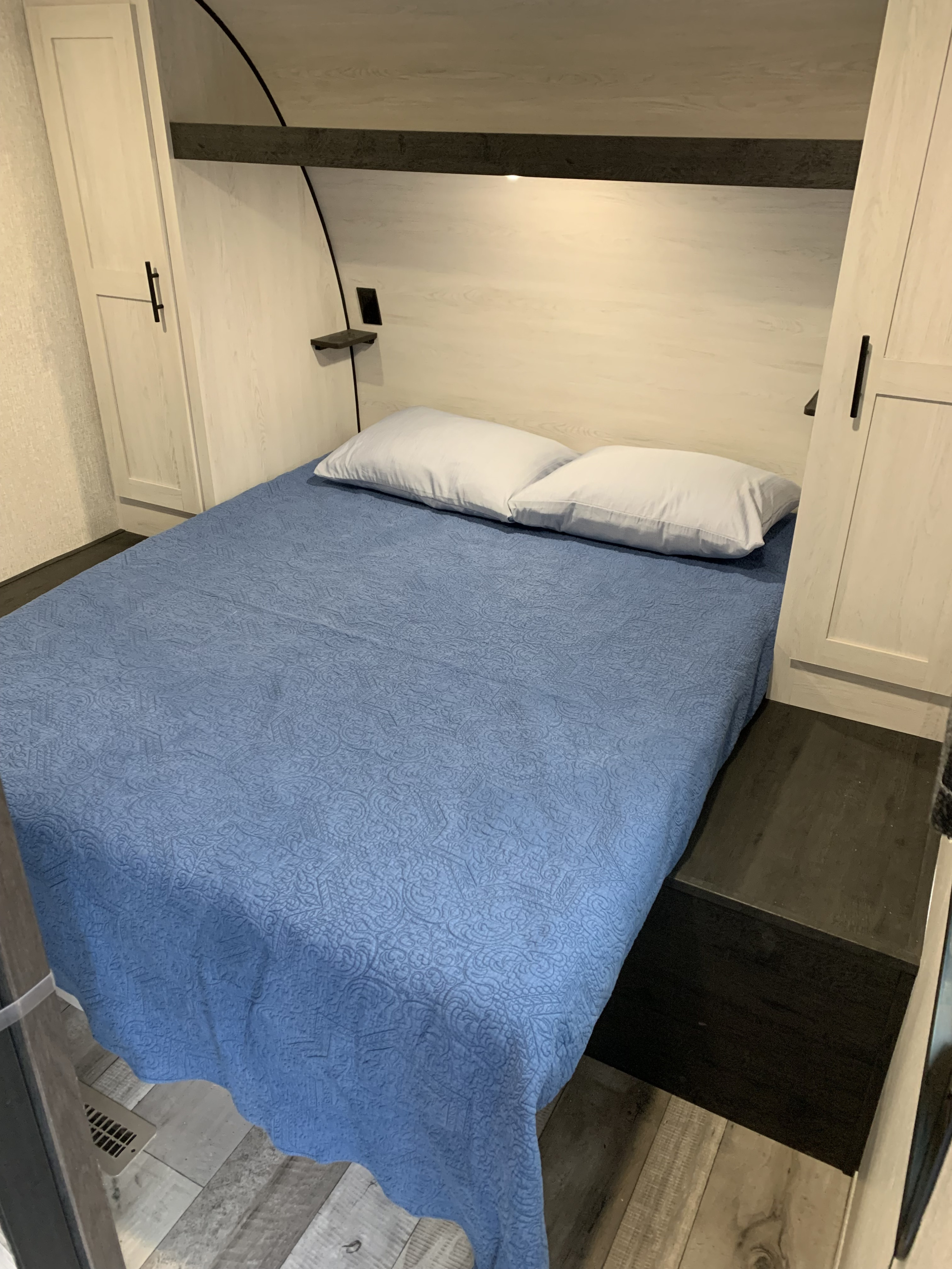 RV rental: Inside a well-appointed RV bedroom with a blue quilted bed, twin white wardrobes, and functional overhead storage.. KZ Sportsman SE 2022