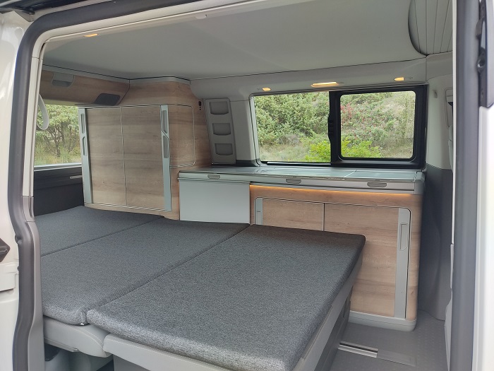 RV rental interior: cozy fold-out bed, integrated kitchenette & storage. Perfect for travel adventures.. Volkswagen California Coast T6.1 DSG7 2023